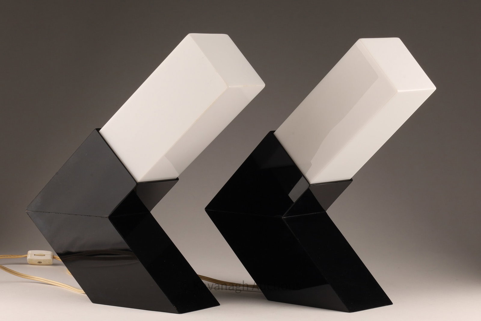 Pair 1980s Black and White Acrylic Modernist Memphis Style Lamps: A pair of 1980s modernist lamps, Postmodern Memphis Style design. Characterized by bold geometric forms and sharp contrast, these lamps utilize bent acrylic (often referred to as Lucite or Perspex) to
