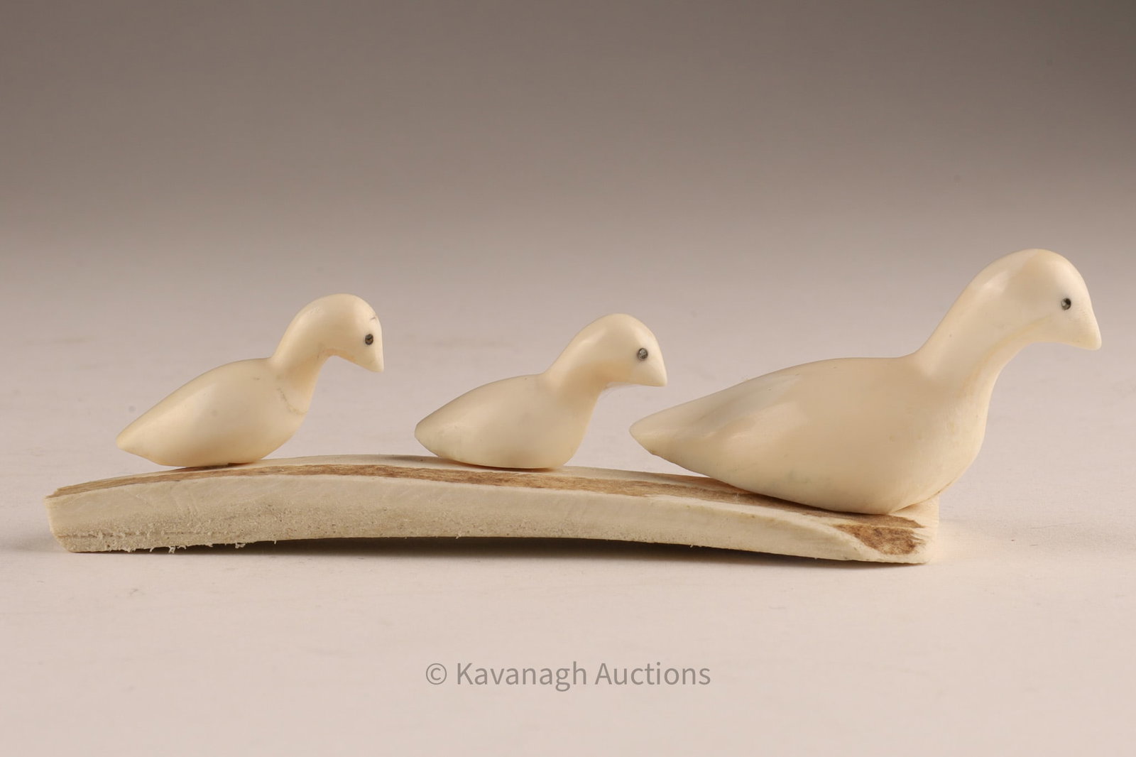 Jacqueline (Pelly Bay) Inuit Carved Goose Family on Base: Small Inuit carving depicting a family group of three geese arranged in procession atop a bone base. The birds are finely carved with smooth, rounded forms and inset dark eyes, the largest figure lead