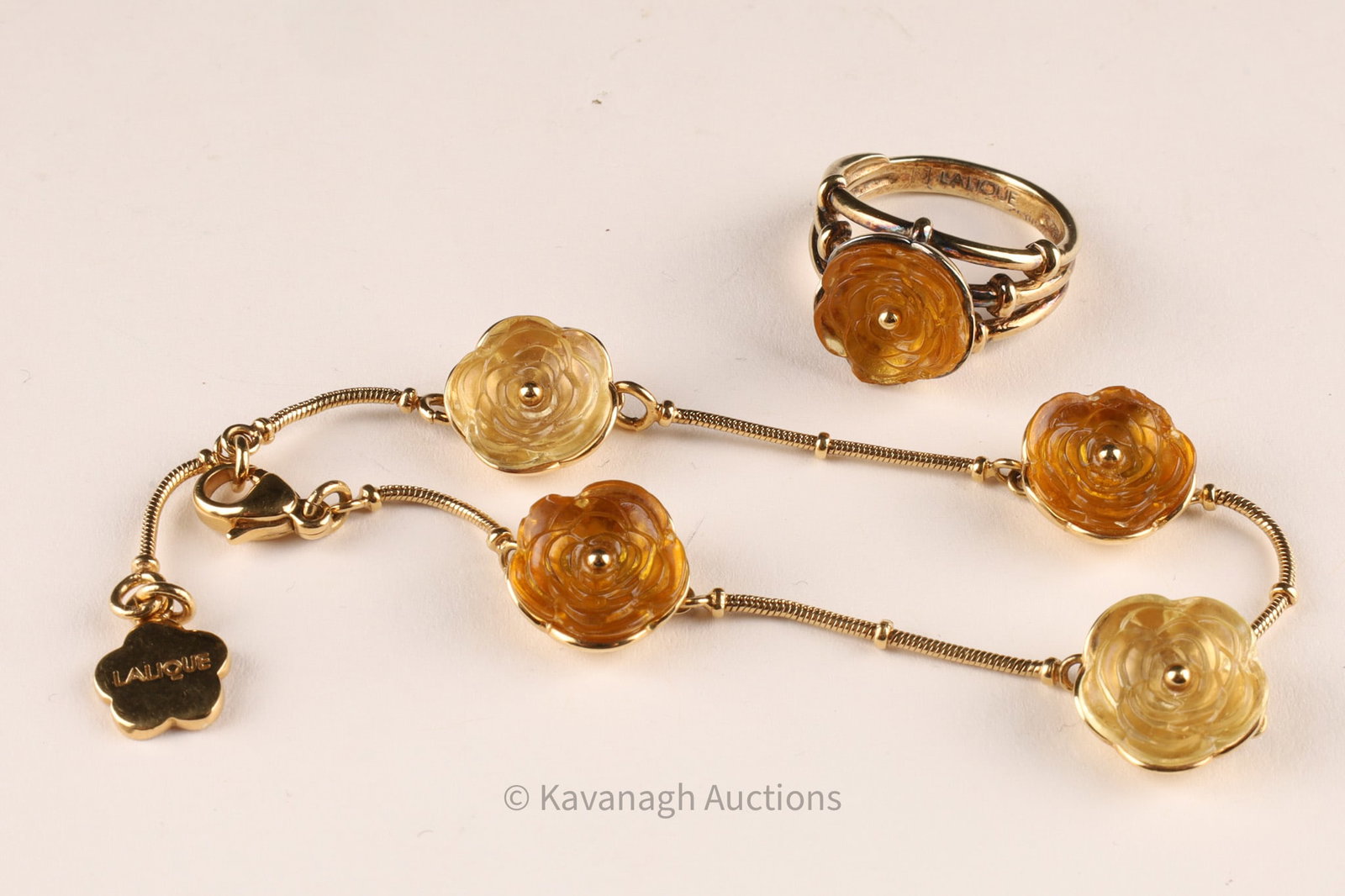 Lalique Gilt Metal and Crystal Floral Bracelet and Ring Set: Lalique jewelry set comprising a bracelet and matching ring, each featuring molded crystal elements in the form of stylized flowers, rendered in warm amber and champagne tones. Details Maker: