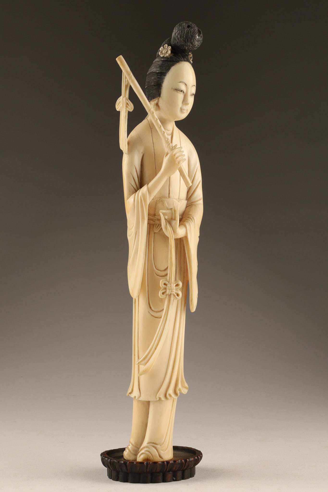 Antique Chinese Carved Figurine of a Woman with Musical Instrument: 19th C. Chinese carved figurine depicting a woman carrying a flute or musical instrument. Dimensions: 11 inches H mounted on wooden base. PLEASE NOTE THIS LOT CANNOT BE EXPORTED FROM CANADA.