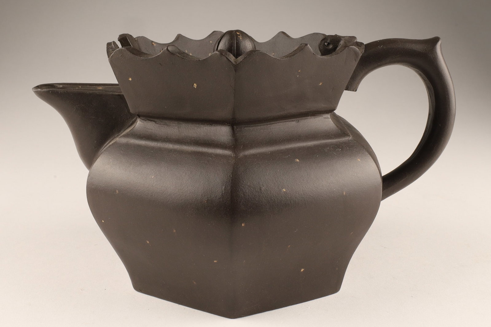 A Signed Dark Brown Chinese Yixing Clay Teapot: A Signed Dark Brown Chinese Yixing Clay Teapot. It features a distinctive lotus-shaped edge on both the body and the lid. Stamps on lid, and underside. Dimensions: 5 inches H x 8.5 W.