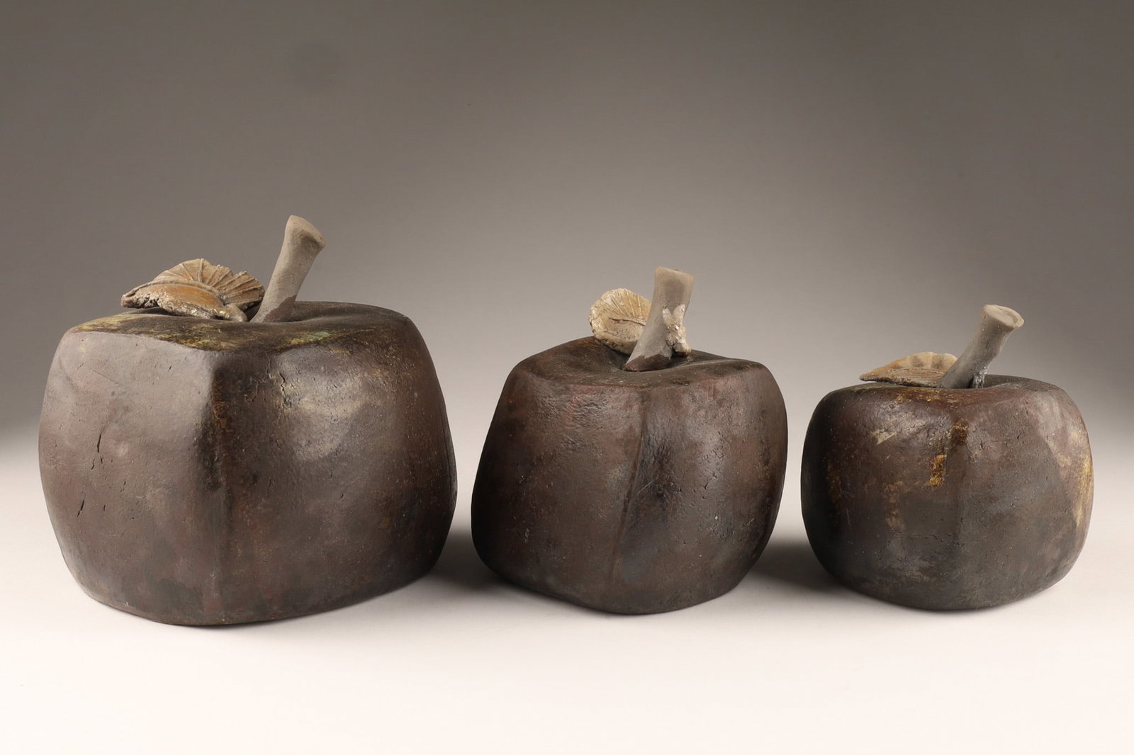 A Collection of Japanese Art Pottery Ceramic Stylized Apples: A Collection of Japanese Art Pottery Ceramic Stylized Cubist Apples. With a glazed surface and applied stems and leaves. Dimensions: Largest measures 5 inches cubed, smallest measuring 4 inches H x 3 