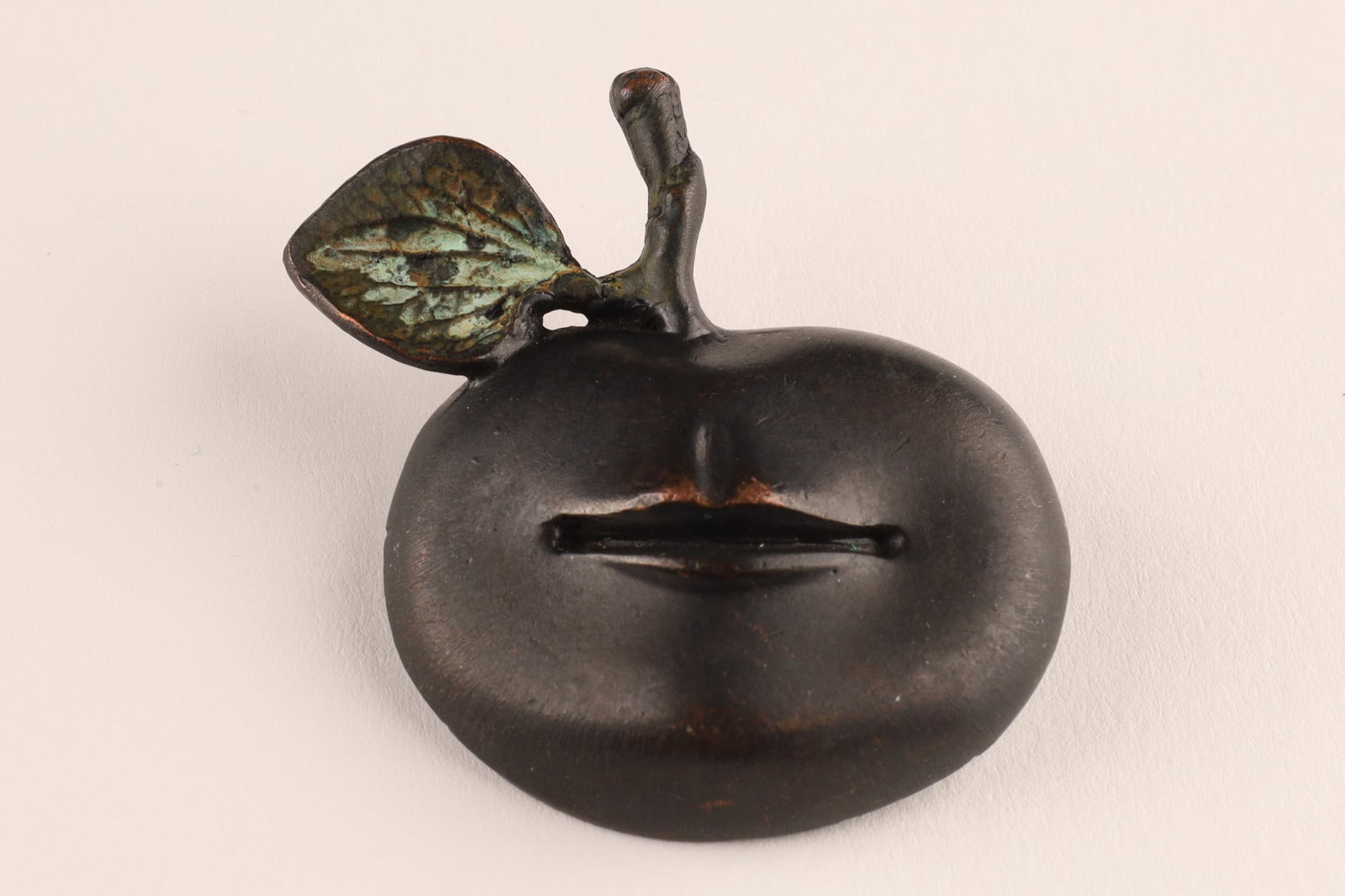 Claude Lalanne Bronze Pomme Bouche Apple Brooch Pin: Pomme Bouche apple brooch by Claude Lalanne, cast in patinated bronze with verdigris leaf. The stylized fruit incorporates Lalanne’s signature surrealist motif of sculpted lips emerging from the app