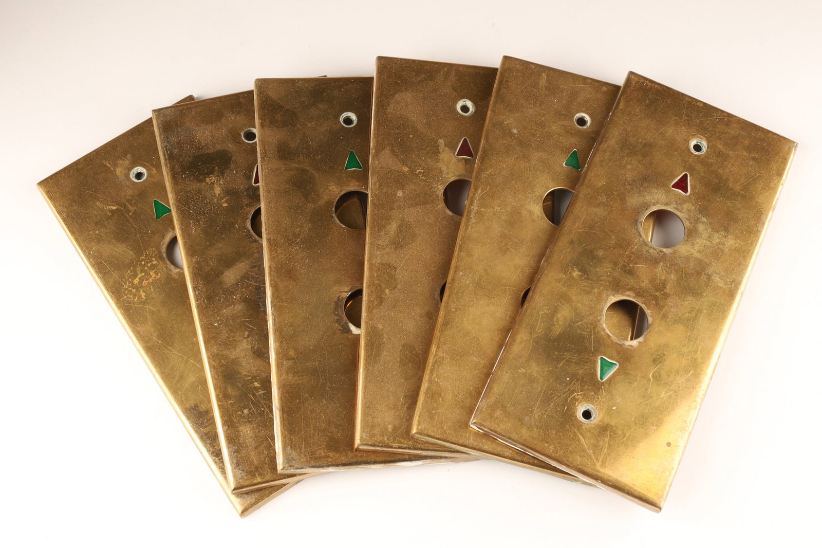 A Collections of Art Deco Antique Brass Elevator Button Plates: A collection of five Art Deco style elevator button plates, made of brass and coloured lenses. Item Type: Antique elevator hardware, possibly from the early 1900s Art Deco period. Features: Includes r