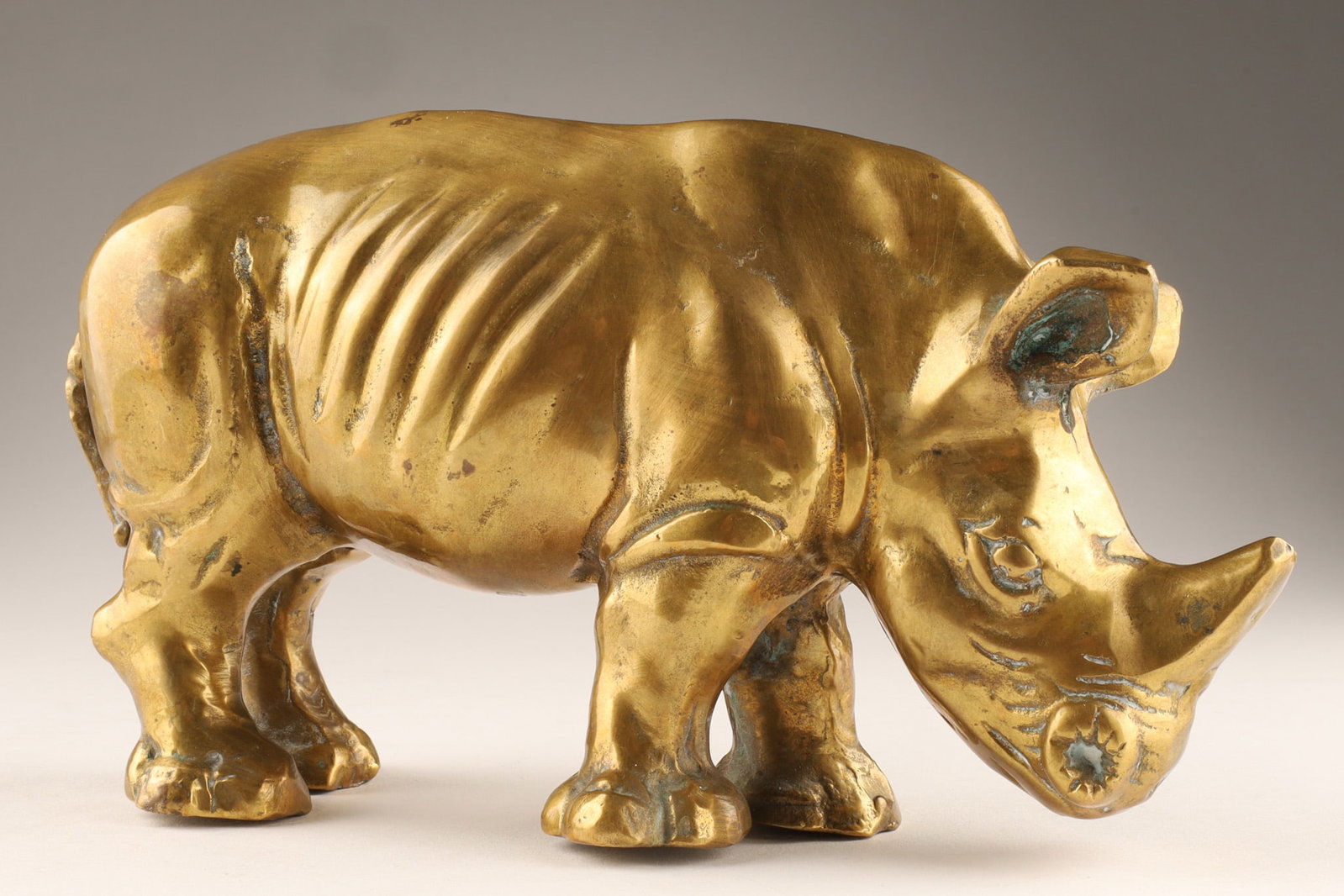 Vintage Brass Rhinoceros Figurine: A vintage brass rhinoceros figurine, approximately mid-century period. Material: Brass with a natural patina. Dimensions: 5 inches H x 9 L.