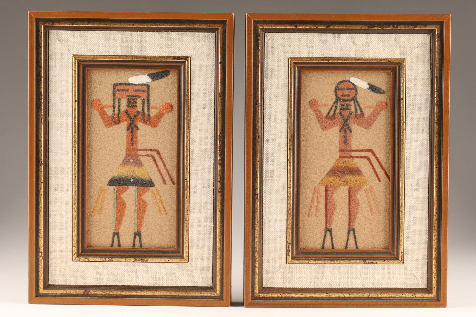 Pair of Native American Navajo Sand Paintings Depicting Gods: A pair of vintage Native American Navajo sand paintings depicting Gods figures, created using natural coloured sand and rocks on a backdrop, framed in wood. Dimensions: Images measure 6 inches H x 3 W