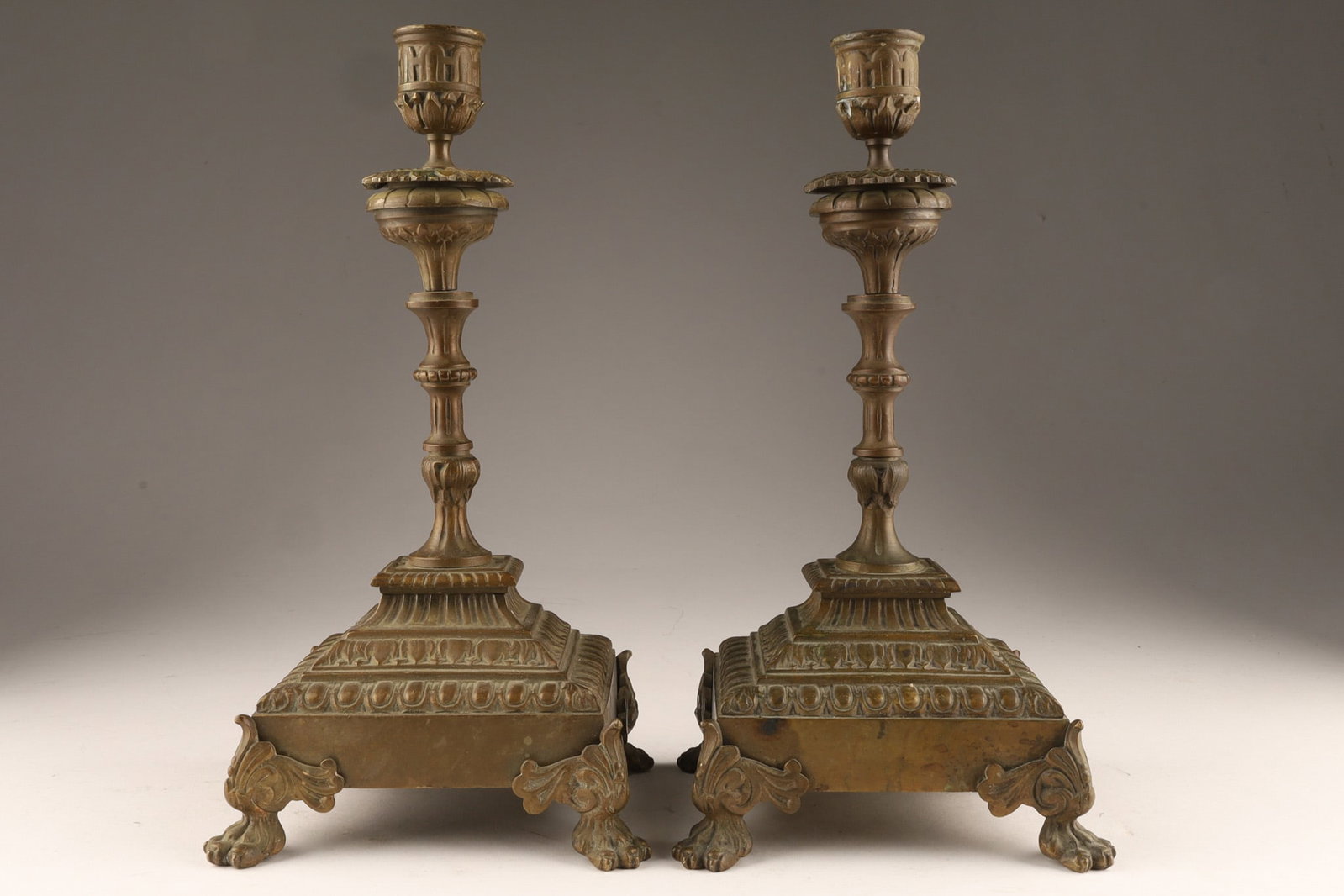 19th C Renaissance Revival Bronze Lion's Paw Egg and Dart Candlesticks: 19th-century bronze candlesticks featuring egg and dart pattern and rest on lion's paw feet in the Renaissance Revival or French Empire styles. Dimensions: 11 inches H x 6 W. Condition: One bold
