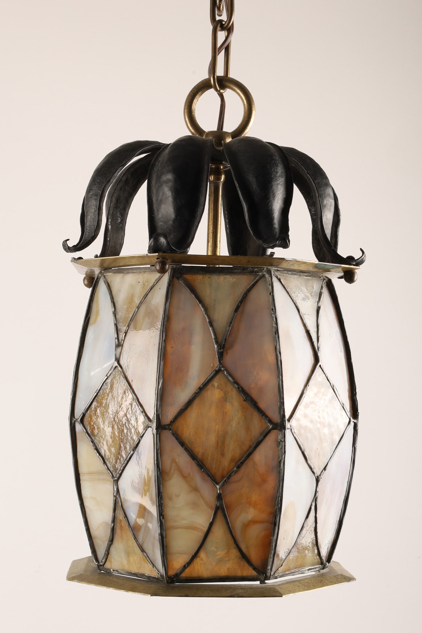 Art Nouveau Style Leaded Slag Glass Pineapple Pendant Light Fixture: Art Nouveau / Arts and Crafts style pendant light fixture featuring a stylized pineapple-form shade composed of marbled slag glass panels within a leaded metal framework. The dark patinated metal crow