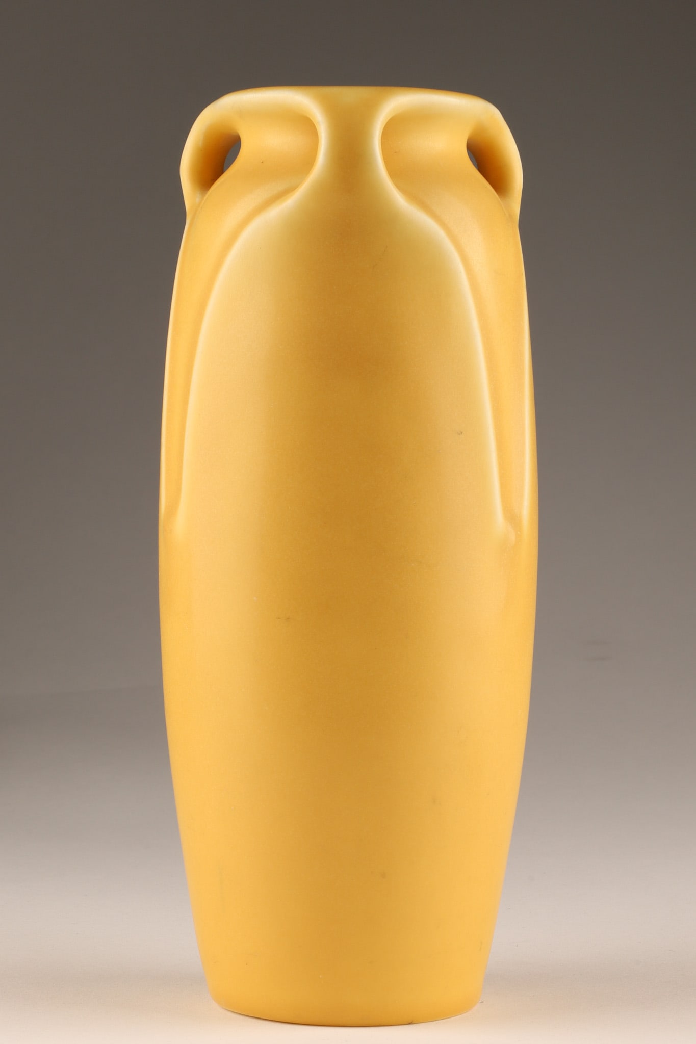 Antique Arts and Crafts Rookwood Pottery Matte Yellow Handled Vase: Antique production vase crafted by Rookwood Pottery Company of Cincinnati, Ohio. The piece features a classic Arts & Crafts silhouette flanked by three minimalist, loop-style stylized handles inte