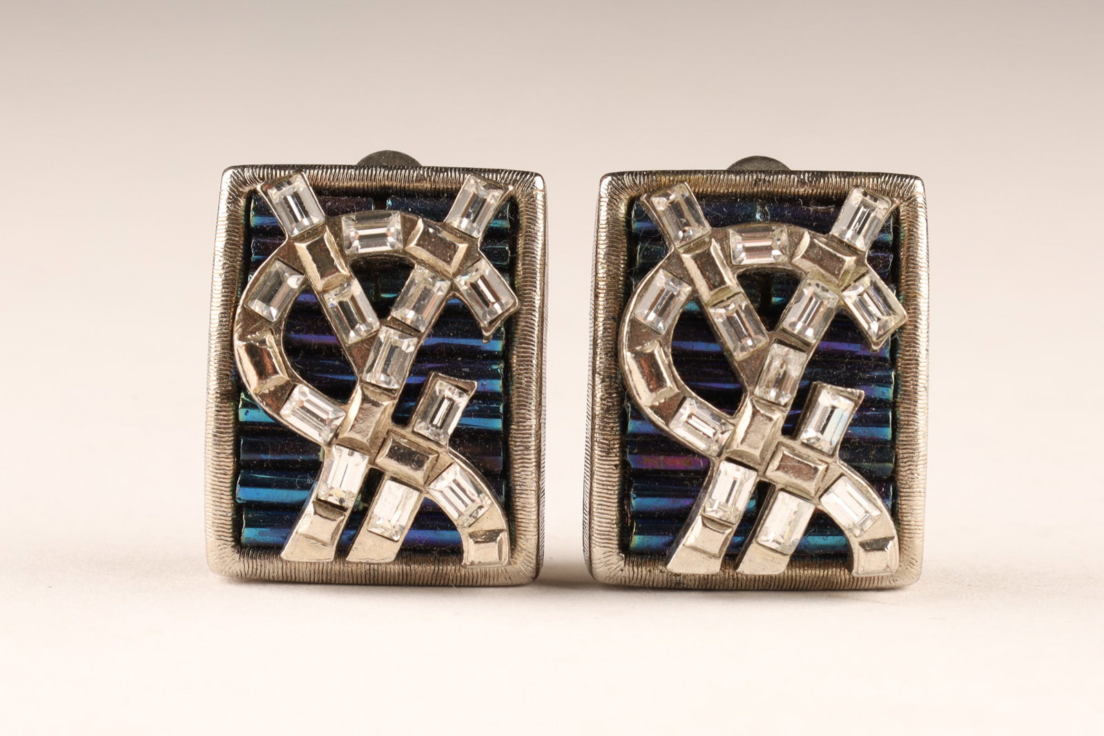 Vintage Yves Saint Laurent Logo Rhinestones Earrings: A pair of vintage Yves Saint Laurent clip on earrings featuring the iconic YSL logo set with rhinestones against a blue glass bead background. Signed YSL Made in France on reverse. Dimensions: 2