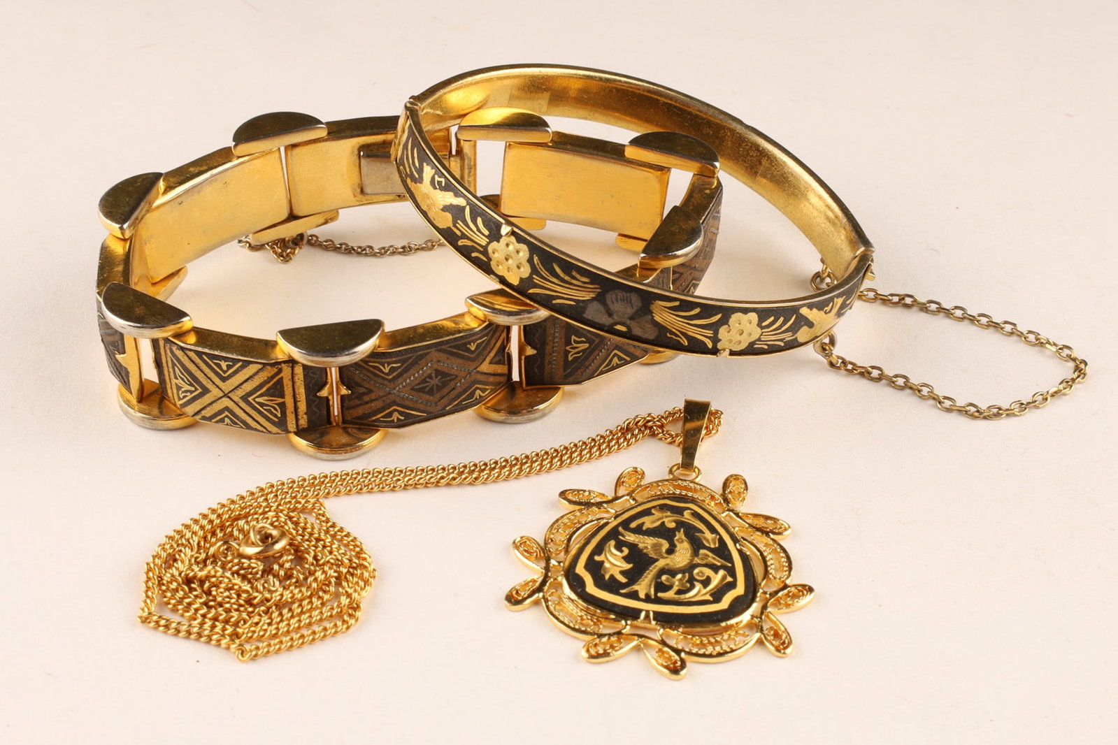 Lot of Gold and Niello Damascene Jewelry, Bracelets and Necklace: A collection of vintage damascene jewelry featuring intricate gold and silver-toned foil inlay set against a rich, black matte background, accented by ornate geometric and floral motifs. Damascene Lin