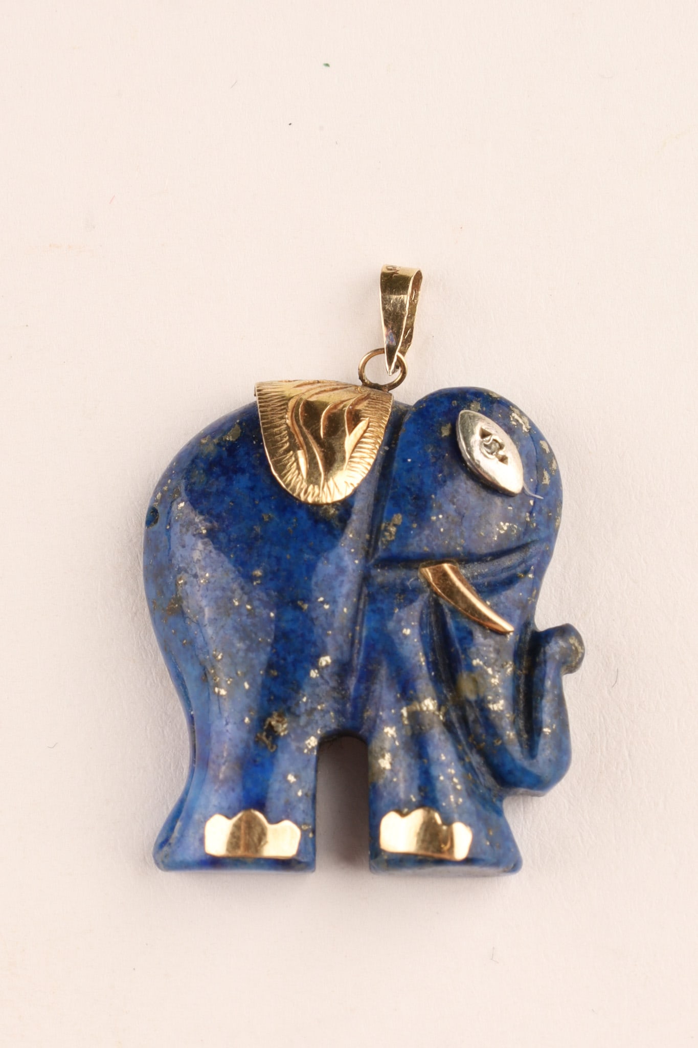 Chinese Lapis Lazuli and 14K Yellow Gold Elephant Pendant Diamond Eye: Chinese 14K gold carved lapis lazuli elephant pendant featuring gold accents on the tusks, feet, and blanket as well as a diamond set eye. Dimensions: 33 x 23mm, total weight 6.9 grams.