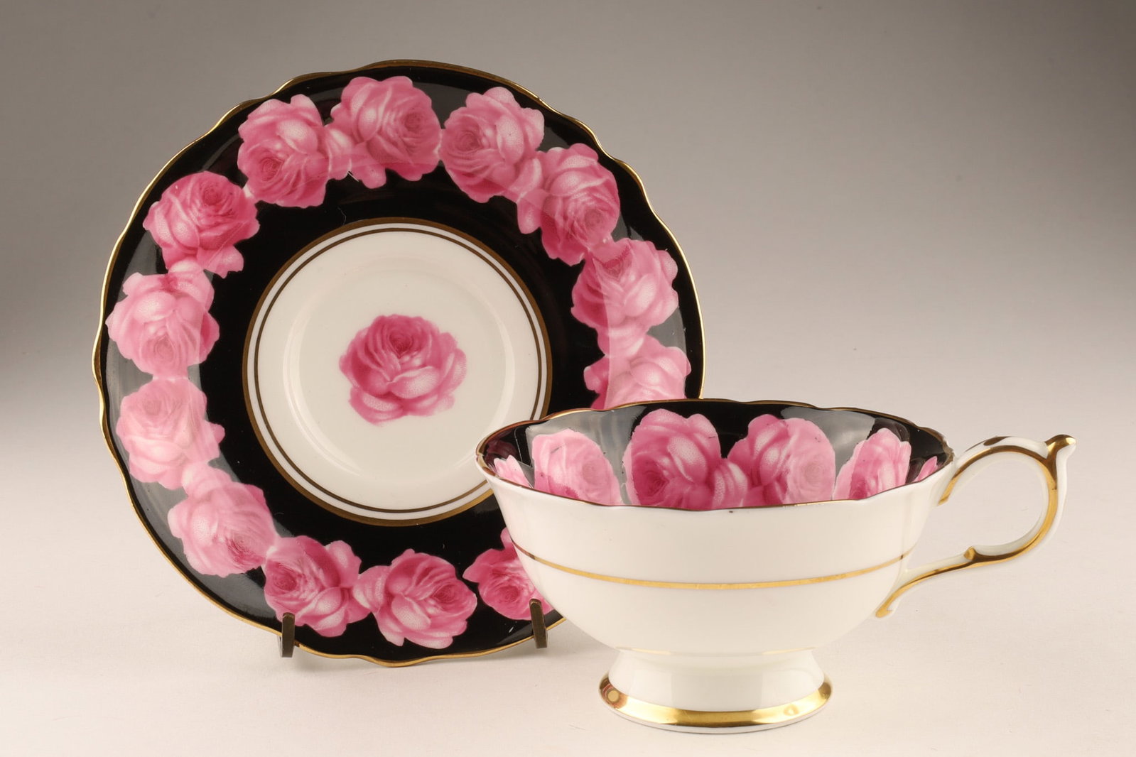 Paragon Queen Mary Cabbage Rose on Black Ground Teacup 1940s: A stunning English white bone china teacup and saucer by Paragon China of Staffordshire, the border circling with hand painted pink cabbage roses on a black ground, the centre with a single hand-paint