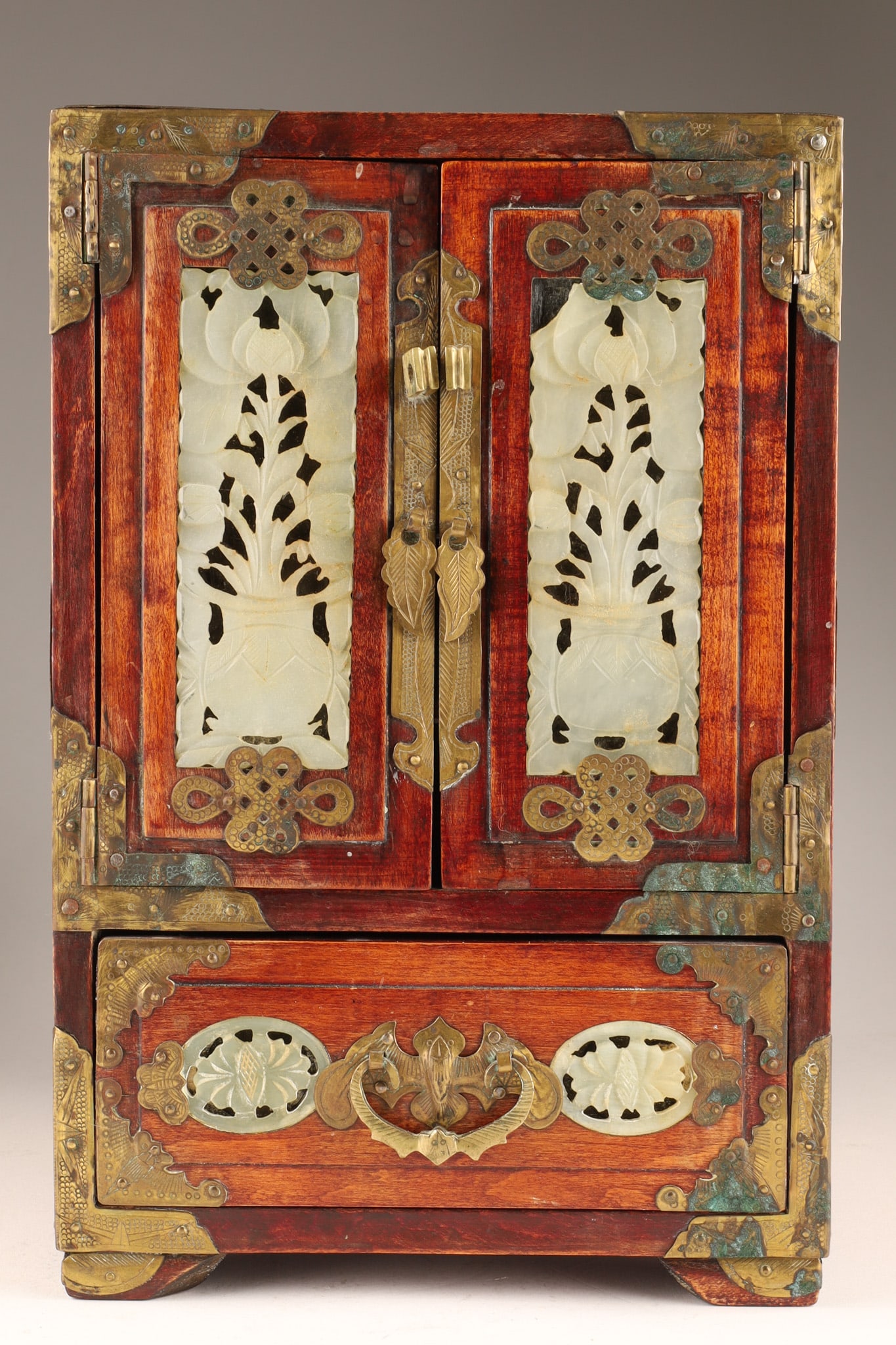 Chinese Hardwood and Jade Inlay Jewelry Cabinet: A Chinese hardwood miniature jewelry cabinet featuring double doors inset with two prominent, hand-carved reticulated jade or hardstone panels depicting stylized floral and botanical motifs with ornat