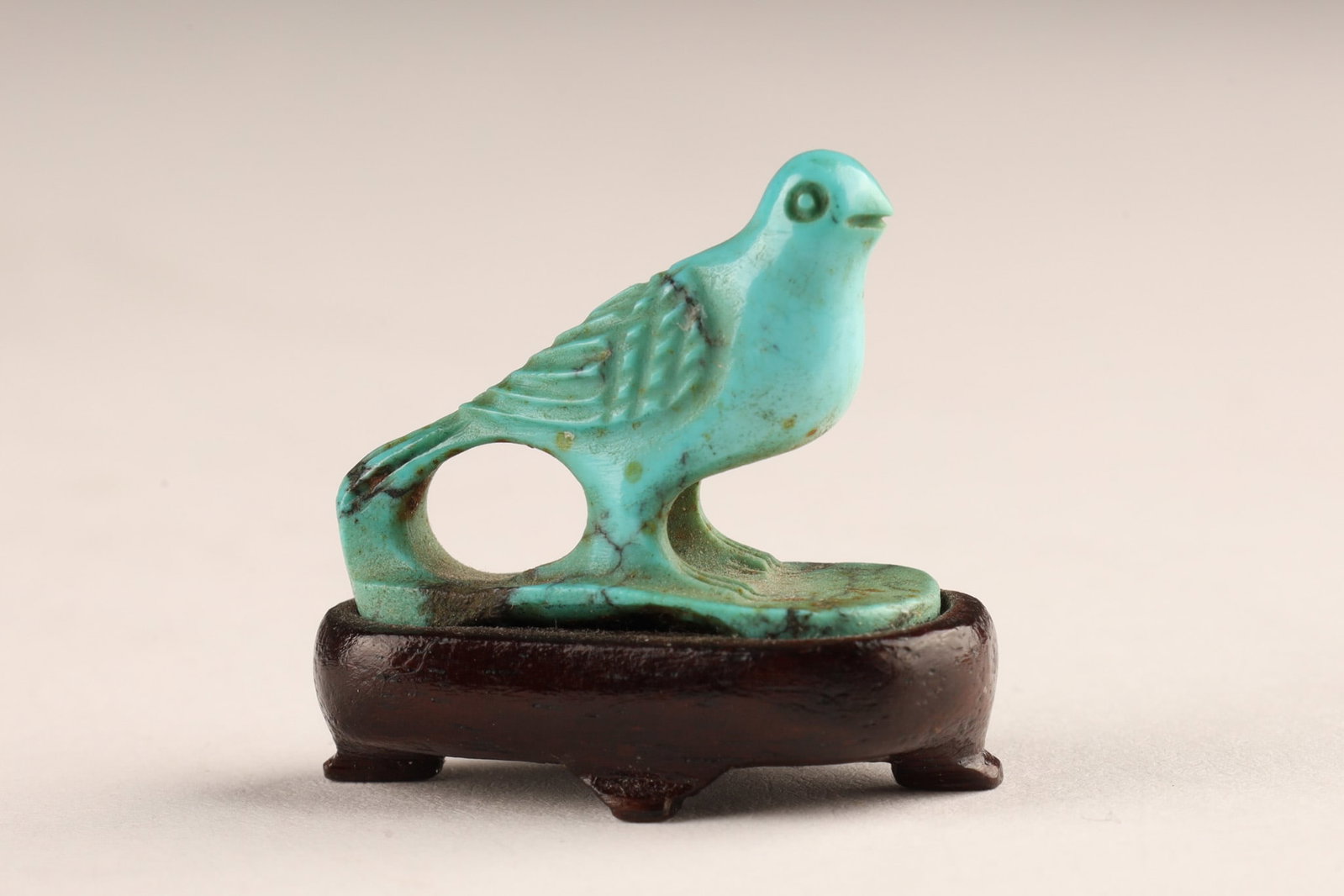 Chinese Miniature Carved Turquoise Bird Figurine on Wooden Stand: A finely hand-carved natural turquoise stone figurine depicting a bird in profile with detailed feather incisions. Rests upon a custom-fitted, dark-carved miniature Chinese wooden display stand. Stand