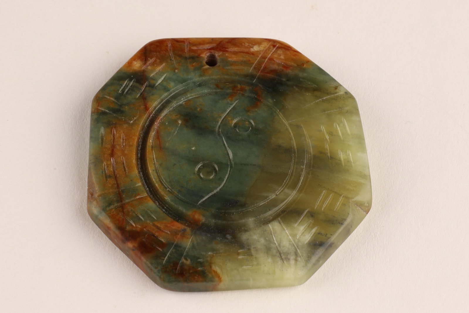 Chinese Carved Octagonal Jade or Agate Pendant Yin Yang Design: A Chinese hand-carved octagonal pendant made from stone, jade or agate, featuring a feng shui design with a yin-yang symbol surrounded by the eight trigrams (Bagua).It is often used as a necklace or a