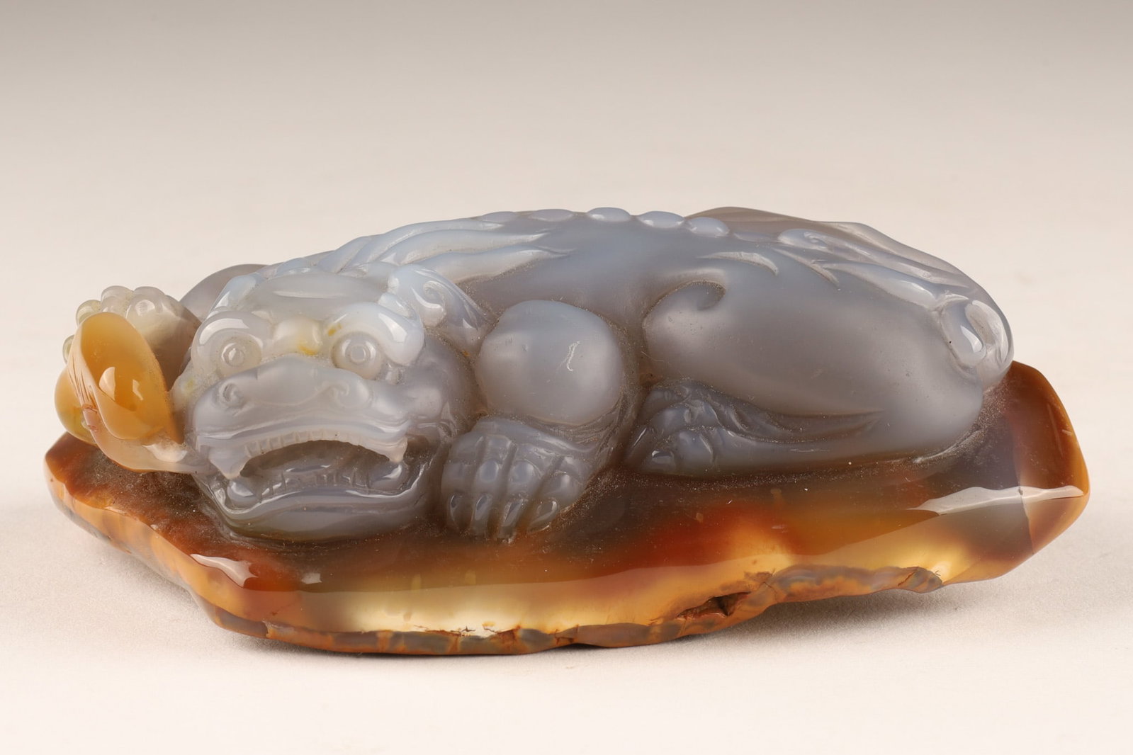 Chinese Carved Lavender Agate Mythical Beast Dragon Lion: Chinese hand-carved lavender coloured agate sculpture of a mythical beast, depicting a Pixiu or a guardian lion (Shi) with brown outer skin or matrix acting as a built-in natural base. Measuring 4 inc