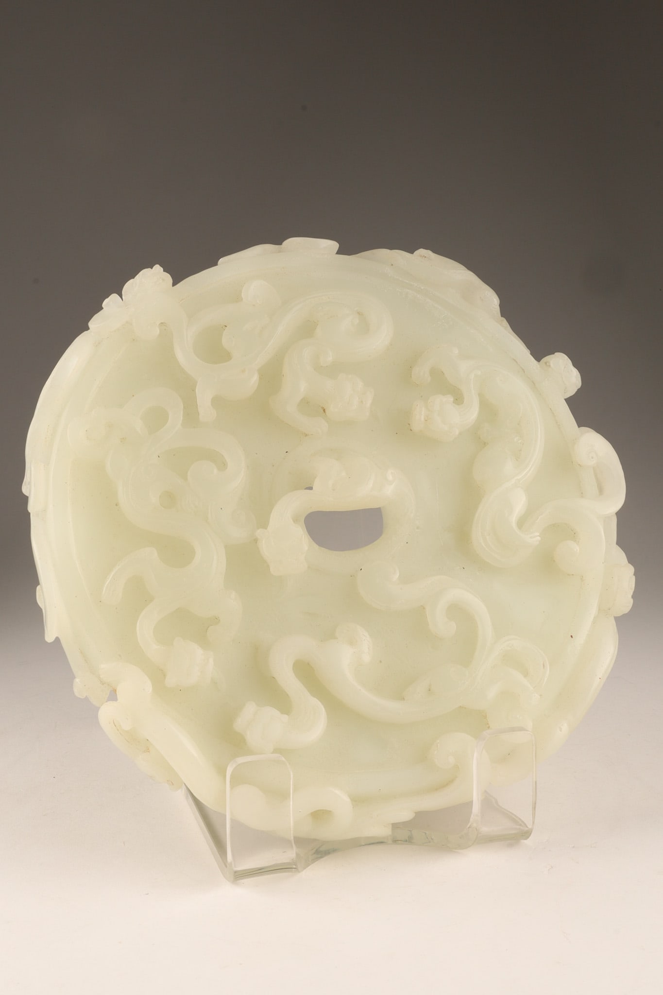 Large Chinese White Hardstone Bi Disc Carved with Chilong Dragons: A finely carved Chinese white hard stone bi disc of circular form, elaborately decorated in high relief with intertwined chilong dragons amidst scrolling clouds. Executed in pale white hard stone and 