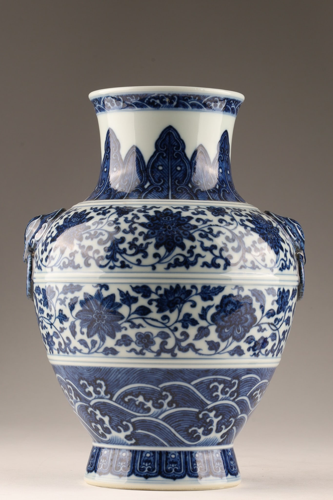 Chinese Blue And White Lotus Scroll Porcelain Vase, 20th C: A Chinese blue and white porcelain zun-form or hu-form vase with archaistic animal mask ring handles and lotus scroll decoration, executed in the Ming revival style, featuring geometric waves, stylize