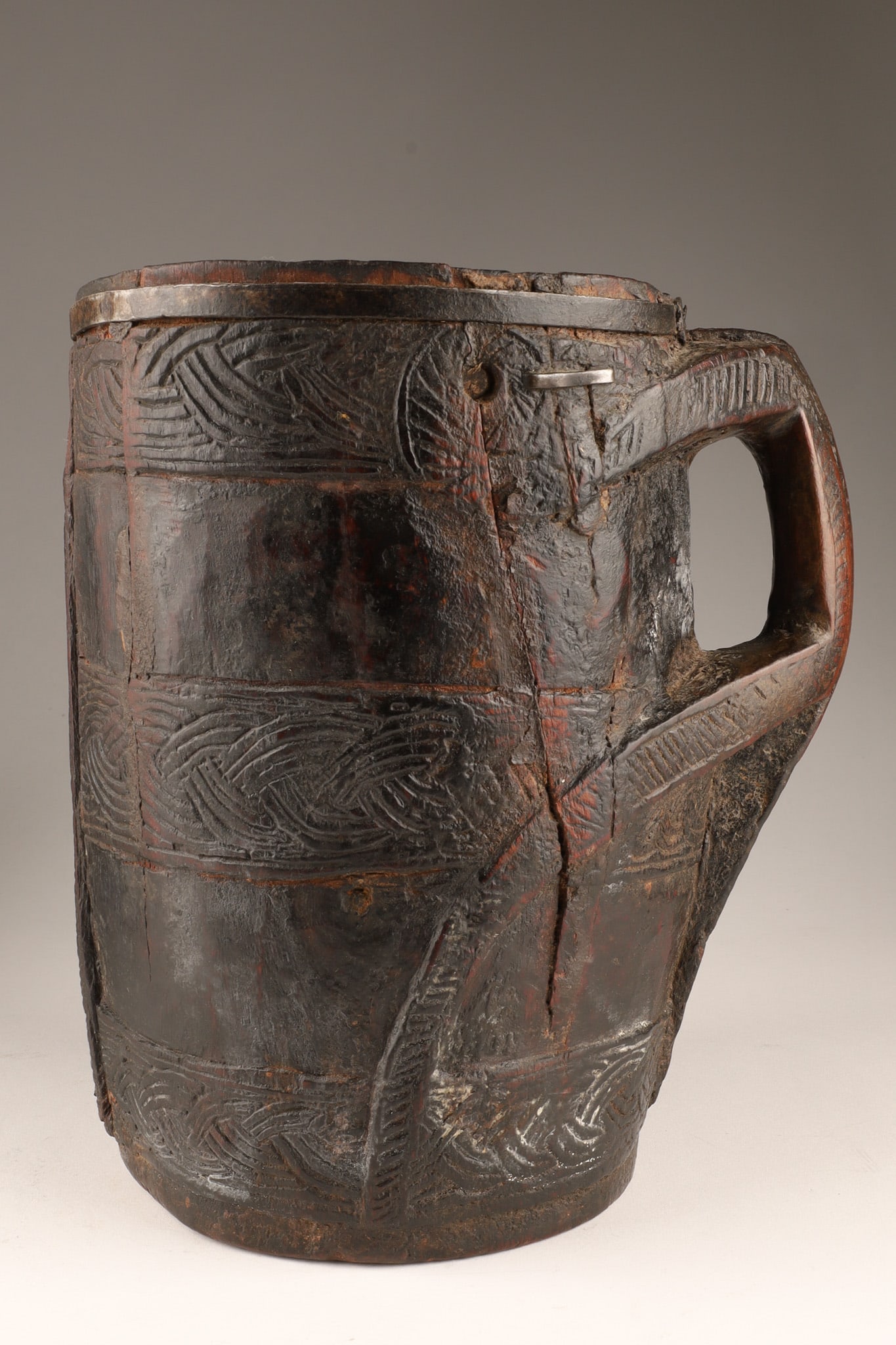 Antique Carved Wood Yak Milk Jug from Nepal: An antique carved wood yak milk jug from Nepal, often attributed to the Sherpa people. The vessel features detailed geometric carvings and iron banding. Measuring 9 inches H x 9 W.
