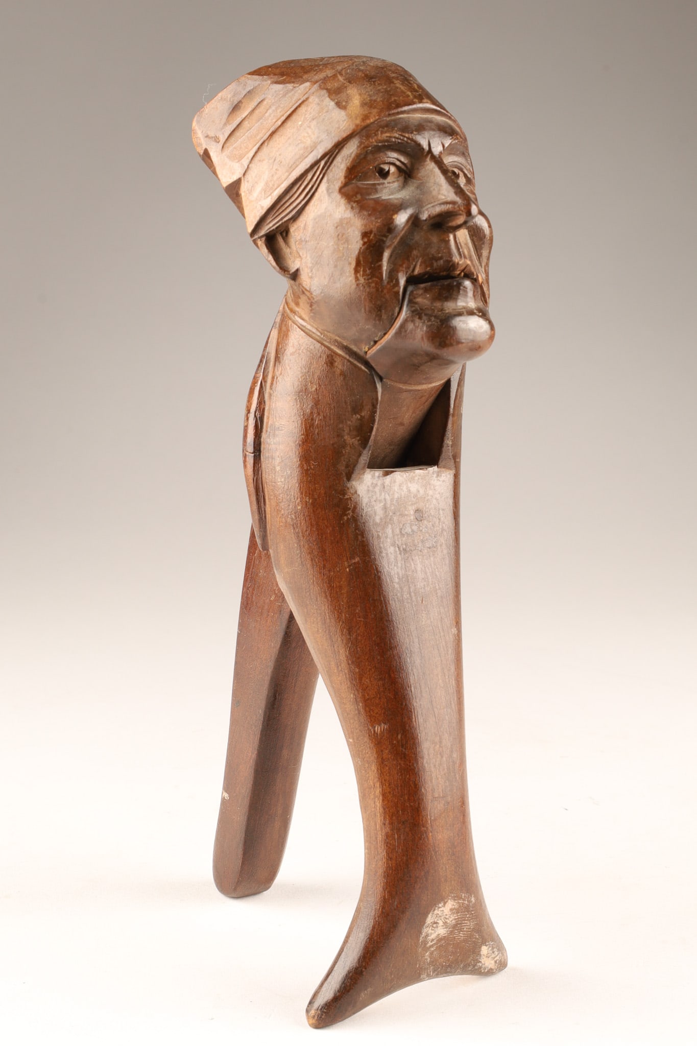 Antique Black Forest Folk Art Nutcracker Figure of an Old Man: An antique Black Forest folk art nutcracker depicting a hand-carved wooden figure of a man wearing a cap. Measuring 8.5 inches.