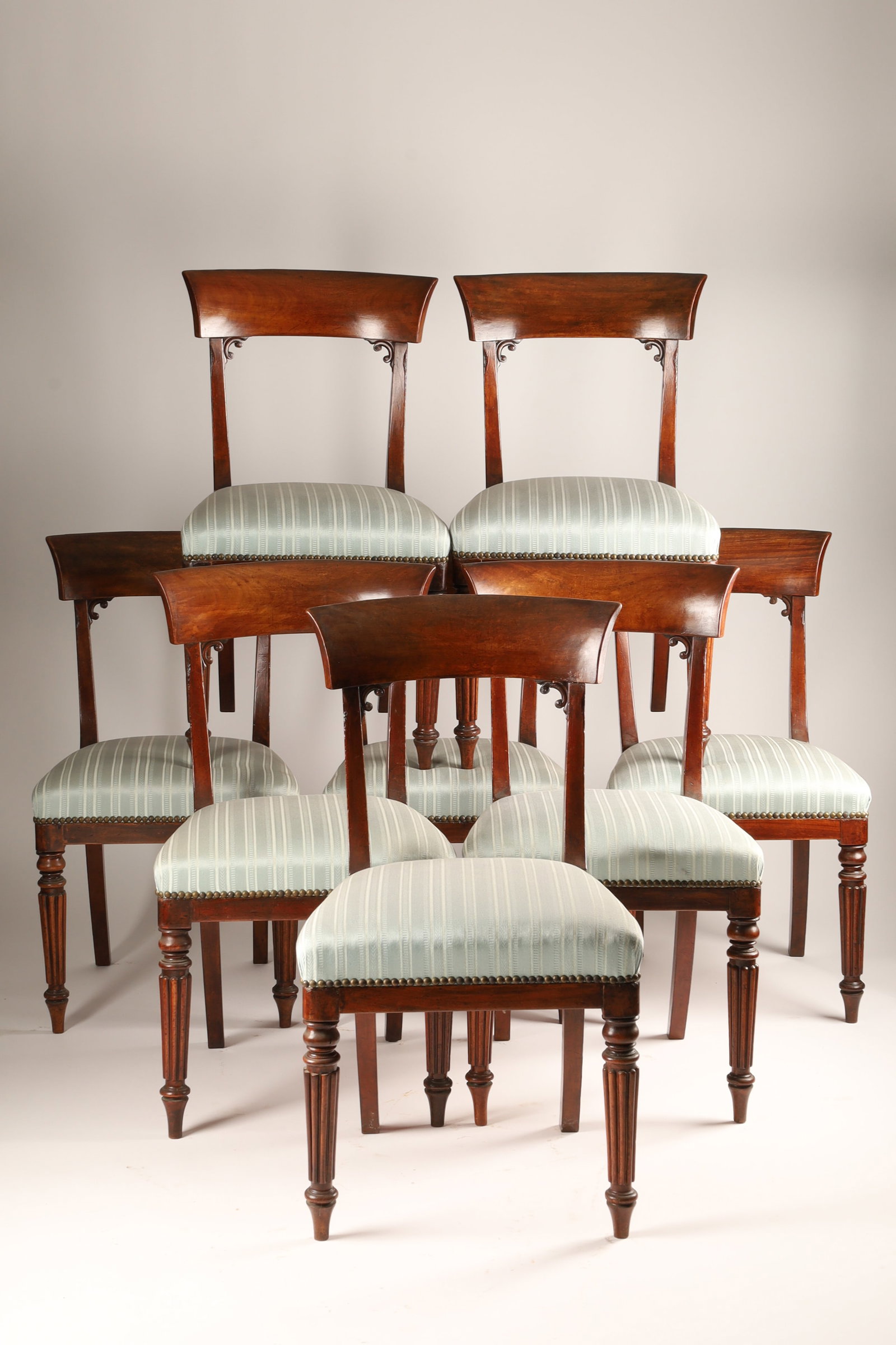 Set of Eight William IV Mahogany Bar Back Dining Chairs: An antique set of eight William IV mahogany curved barback dining chairs dating to the early 19th century (circa 1830). With wide, curved top rails made of highly figured flame mahogany, reeded legs a