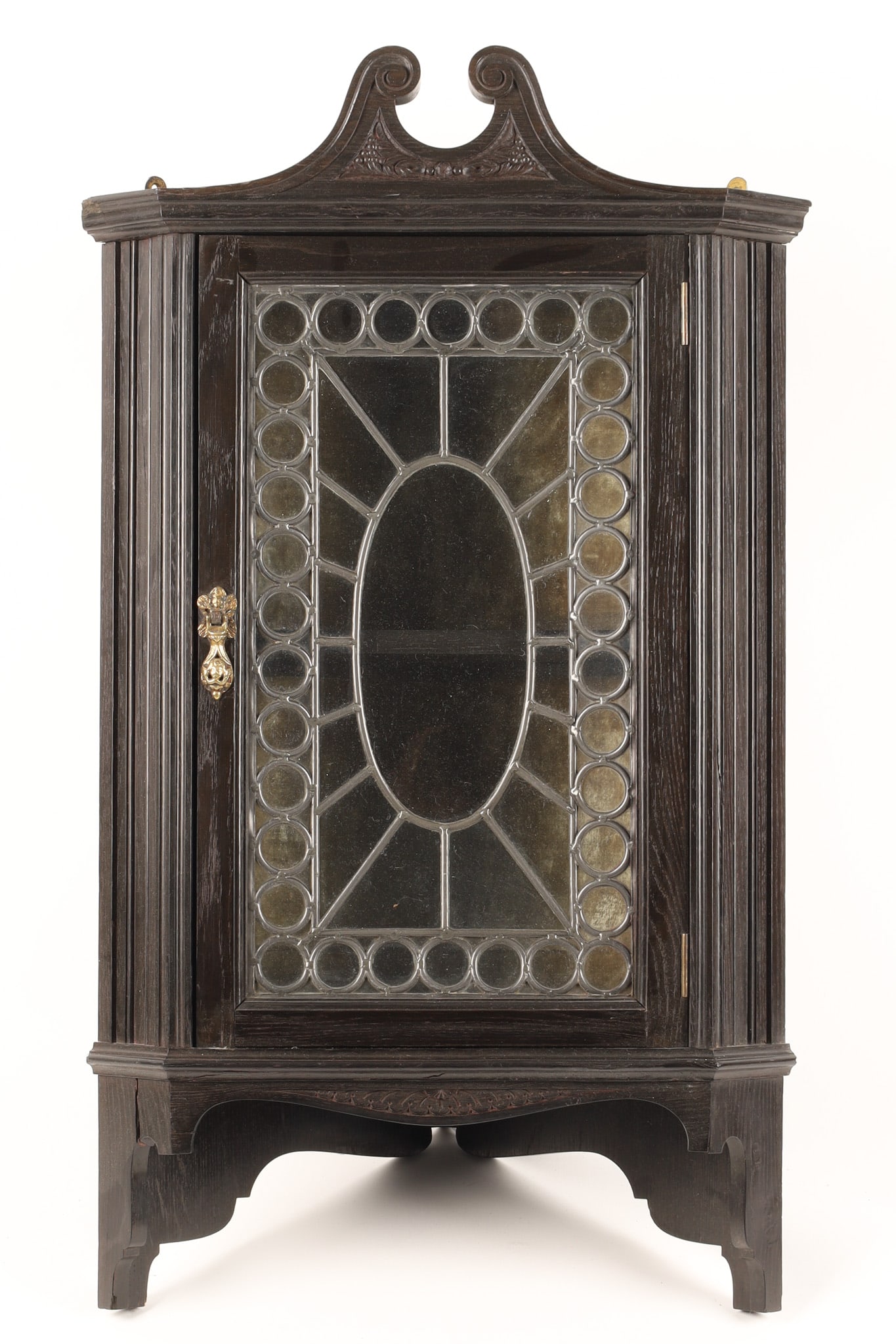 Edwardian Ebonized Oak Arts and Crafts Corner Cupboard: Edwardian period quarter sawn oak small corner cupboard, the ebonized oak featuring a scroll pediment and various carved designs, set with a leaded glass with unique reverse concave oval centre design