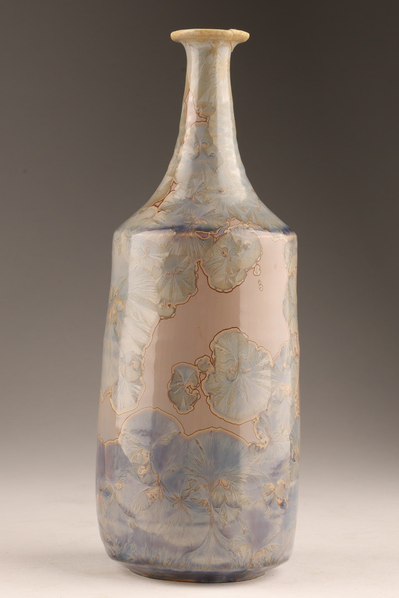 Studio Art Pottery Vase with Floral Crystalline Glaze Signed: A crystalline glaze ceramic vase featuring blue stylized pansies on a pinkish-grey background monogrammed on underside BL (LB?). 9.75 inches H x 3.5 W. Restoration to rim, as shown. 