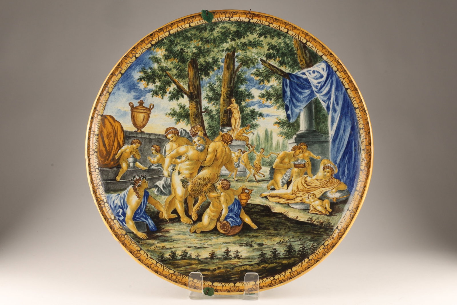Large Antique Italian Majolica Glazed Earthenware Platter Bacchanal Scene: The central composition focuses on Silenus, the elderly, fleshy, and intoxicated tutor of Bacchus (Dionysus), who is depicted being supported by reveling bacchants and satyrs in a lush, wooded classic