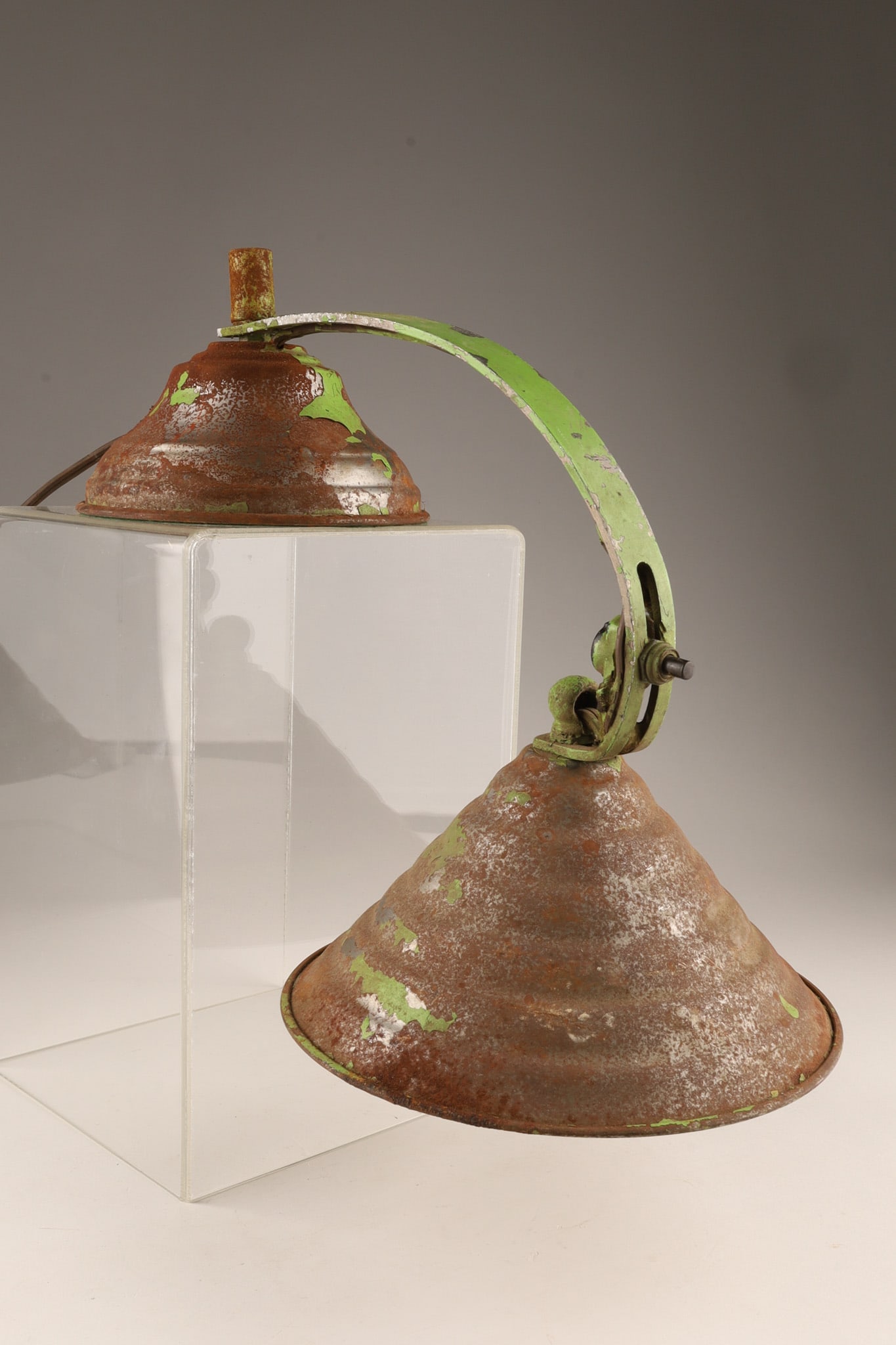 Industrial Art Deco Stepped Counter-Balance Desk Lamp: A vintage industrial counter-balance desk lamp featuring a heavily patinated, weathered finish with remnants of green paint. It features an adjustable arched arm assembly connecting a heavy, bell-shap
