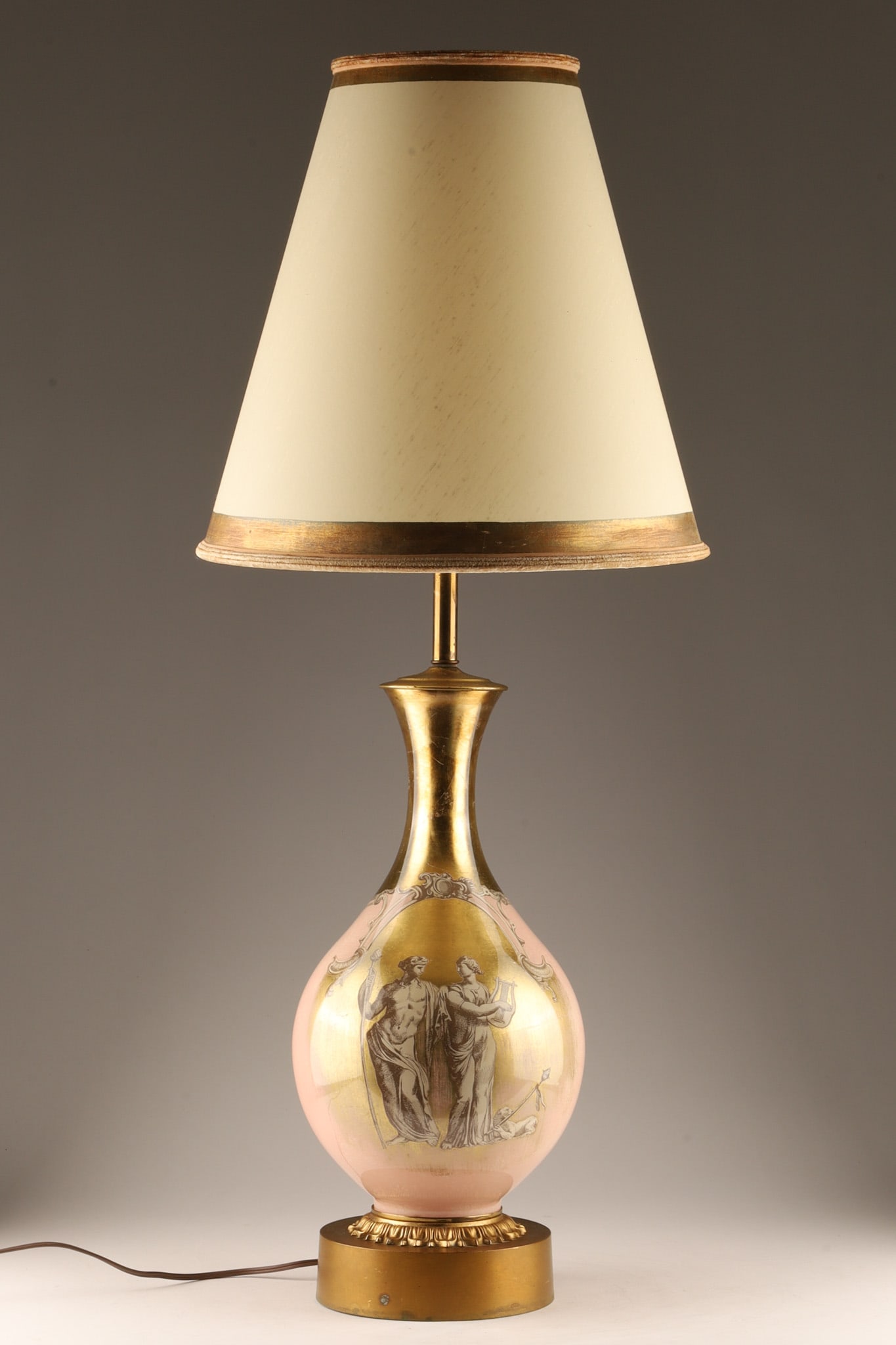 MCM Fornasetti Style Eglomise Pink Lamp and Shade C 1955: A mid-century Hollywood Regency Fornasetti style table lamp, circa 1955. Features an urn-shaped glass base executed in a soft blush pink ground with reverse-painted (verre eglomise) gold leaf overlay 