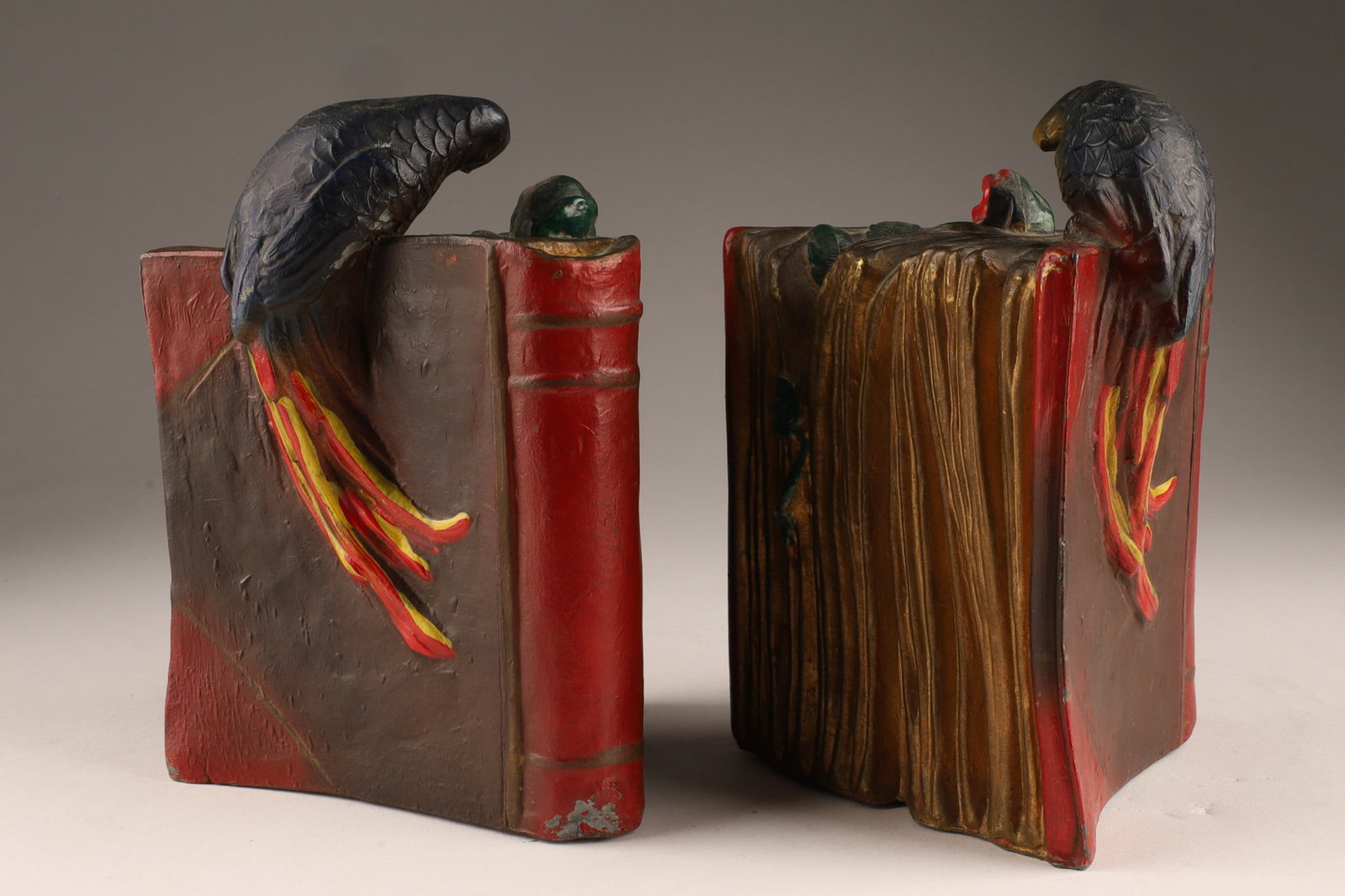 Pair Art Deco Spelter Hand Painted Bookends Parrots on Books: A pair of antique spelter bookends featuring hand-painted parrots perched atop books, likely dating to the 1920s. Unmarked, measuring 6 inches H x 4.5 W x 4 deep.