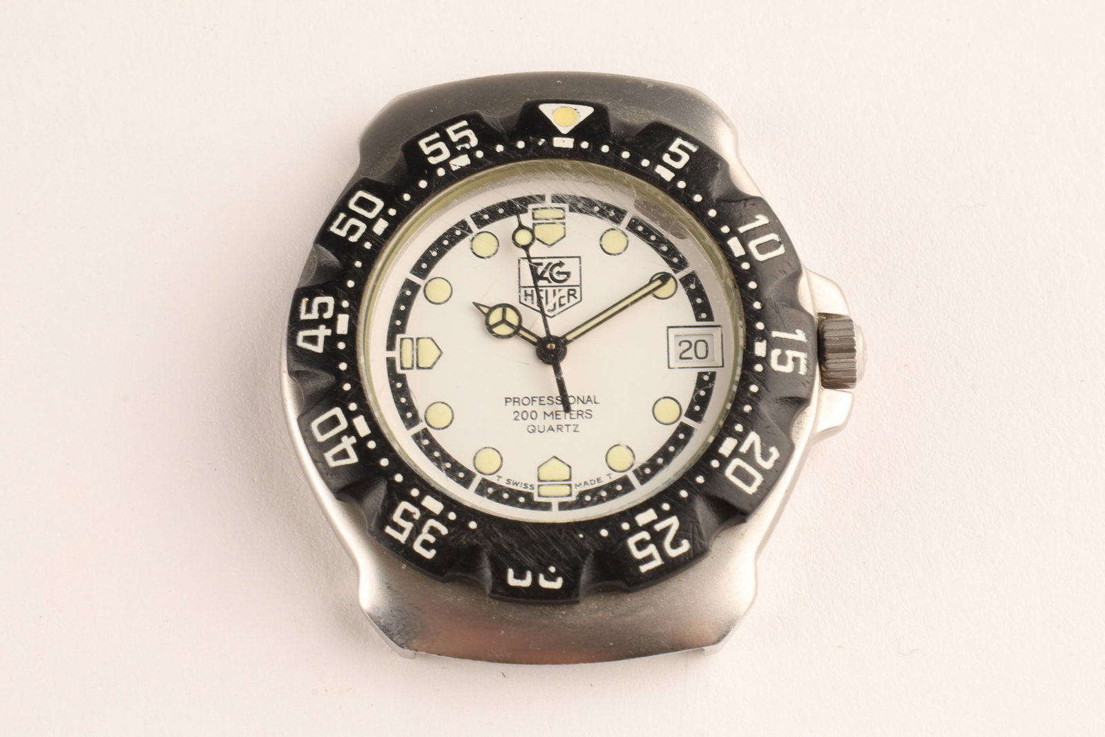 TAG Heuer Formula 1 Professional Stainless Steel 200m 34 mm Quartz Watch: TAG Heuer Formula 1 quartz watch featuring a clean white dial and a bold, notched black bezel, marked on dial, 200 Meters with date window. No strap, needs new battery.