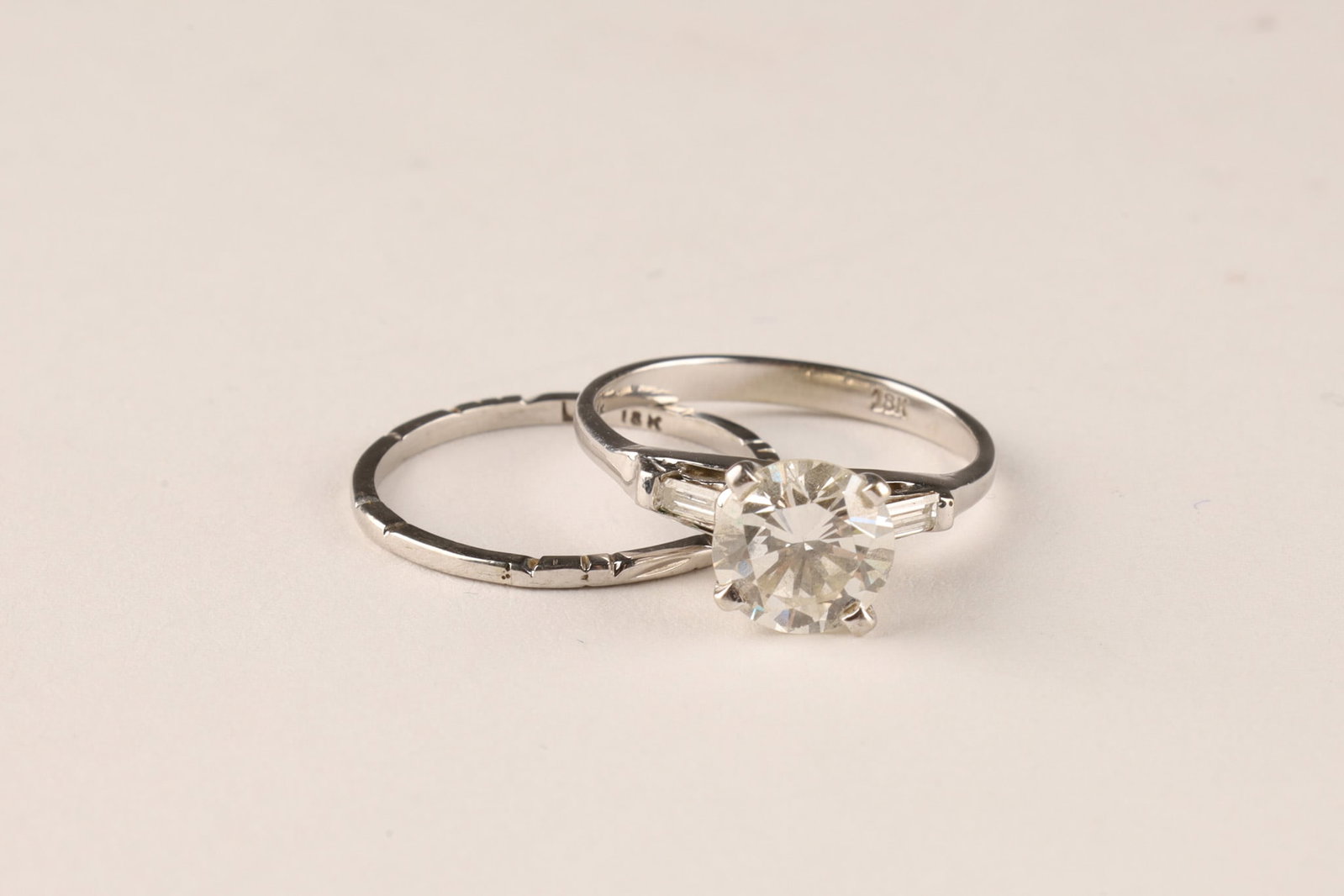 18K White Gold and Diamonds Engagement Ring and Wedding Band Set, Size 5.25: A set composed of one 18K white gold solitaire style engagement ring featuring one four prong set round brilliant cut diamond measuring approximately 7.4mm x 4.3mm, clarity VS2 flanked by two tapered 