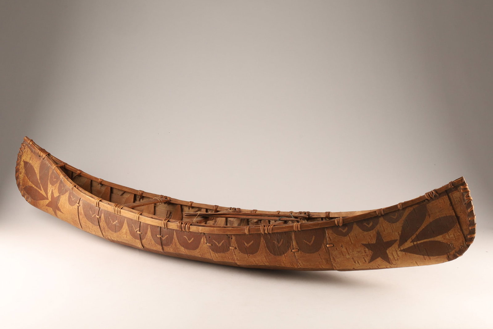 Decorated Birch Bark Canoe Made by the Atikamekw, La Tuque: A beautifully crafted authentic Atikamekw handmade birch bark canoe model from La Tuque, Quebec. This piece showcases traditional First Nations artistry with detailed, etched winter bark woodland moti