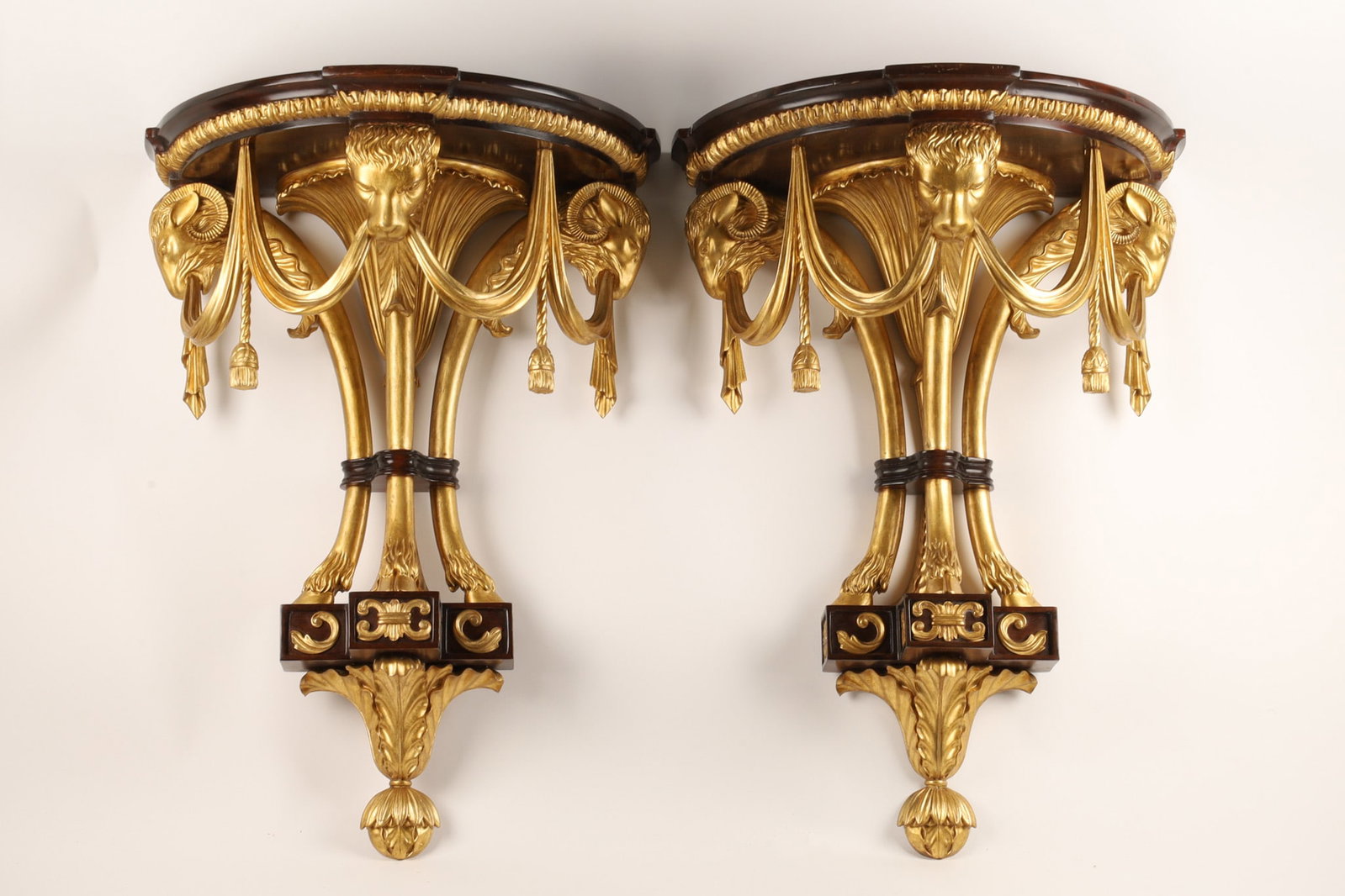French Empire Style Parcel Gilt Wood Wall Brackets Rams Lion: French Empire styled parcel gilt wood wall brackets or shelves, the mahogany shelf above a pair of rams heads and a lions head with tassels and sashes, joining to three cloven hooves, circa 2nd half 2