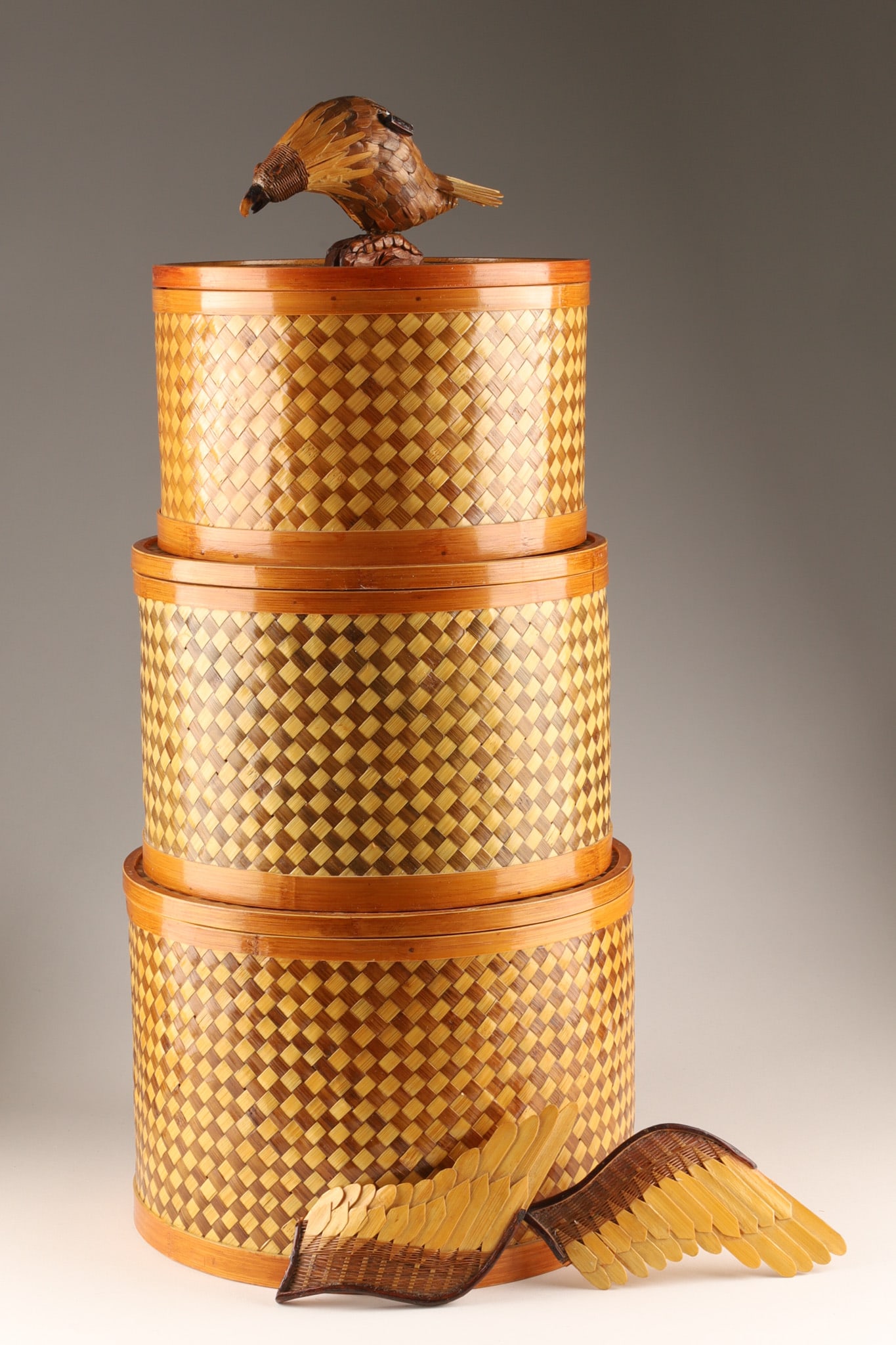 Chinese Shanghai Weave Rattan Bamboo Flying Eagle Boxes, Set of Three: THE SIMON CHANG COLLECTION - Shanghai Handicrafts stack of three round, lidded bamboo and wicker storage boxes with a geometric mosaic pattern, featuring a carved wooden bird figure on top. Dimensions
