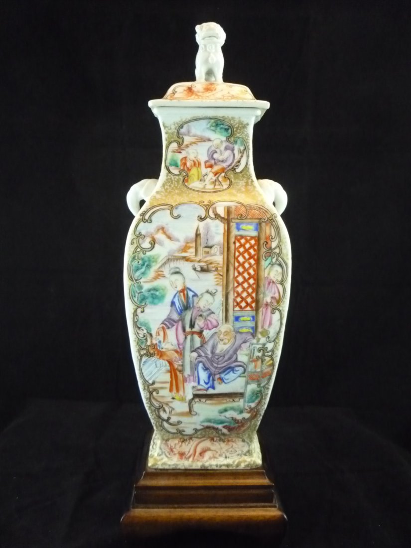 Chinese Porcelain Lidded Vase: Chinese Porcelain Lidded Vase. Decorated with porcelain foo dog and elephant heads on either side. Painted scenes on all sides. Wood base. 16"h x 5"w x 4"d