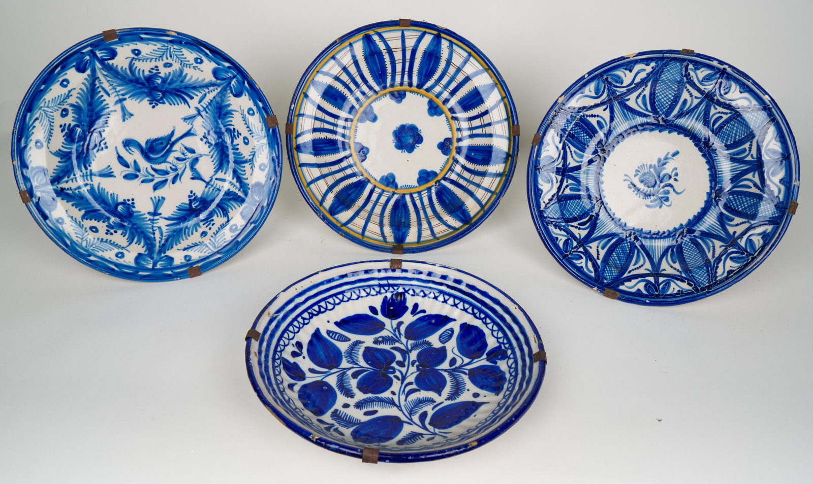 Spanish Fajalauza Talavera (Antique): Four antique plates. 11 3/4 W x 1 3/4 H in. (largest and approximate). All with old hangers. Provenance: Marietta Berman (Czech-Venezuelan artist, 1917 - 1990) acquired in Cuenca, Spain in the mid-197