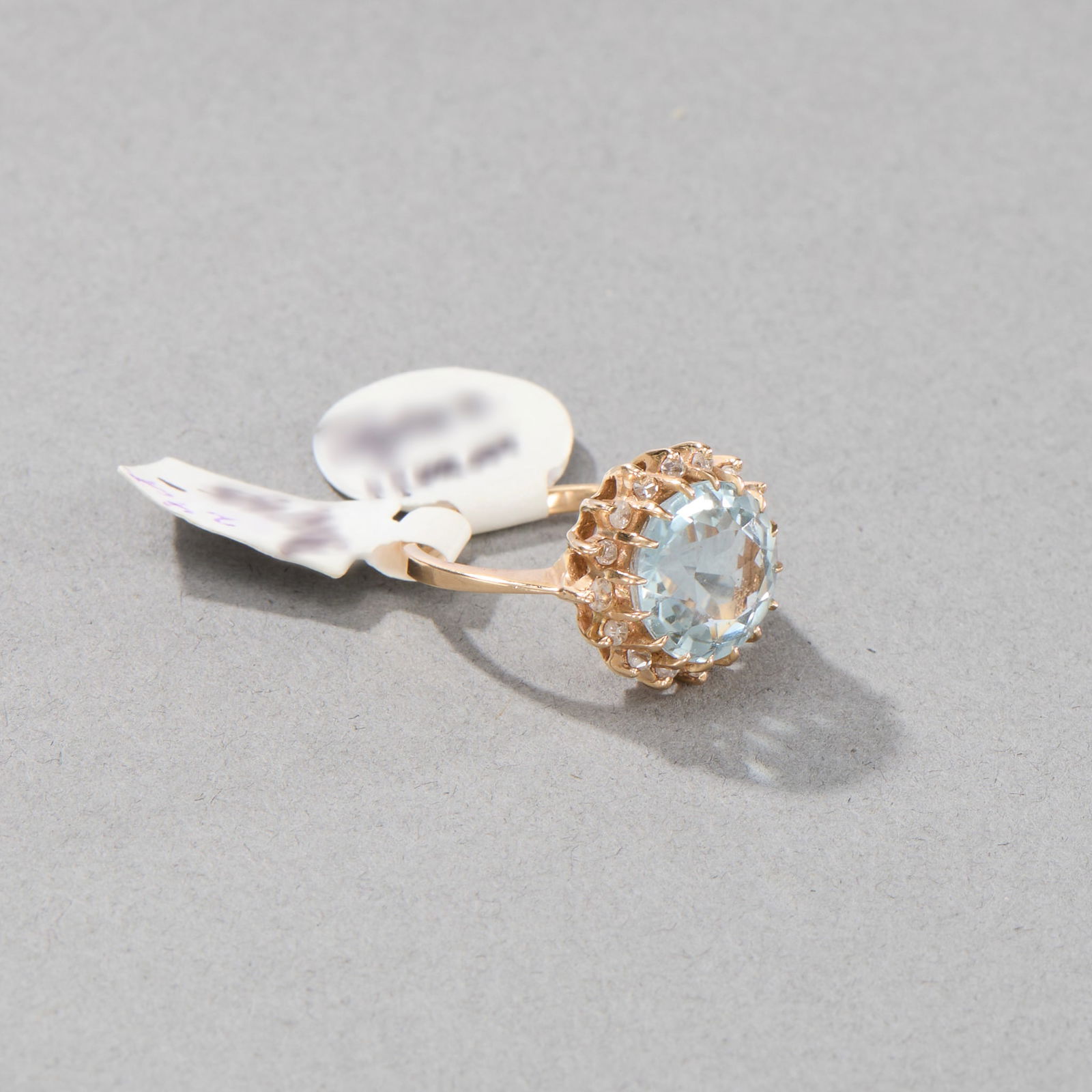 14k Yellow Gold Topaz and Diamond Ring: Round light blue topaz stone encircled by sixteen (16) diamonds set in 14k yellow gold band. Marked 14k on interior band. Ring size: 6; Gross weight: 2.9 dwt. Stone diameter: approx. 12.1 mm. Stone he