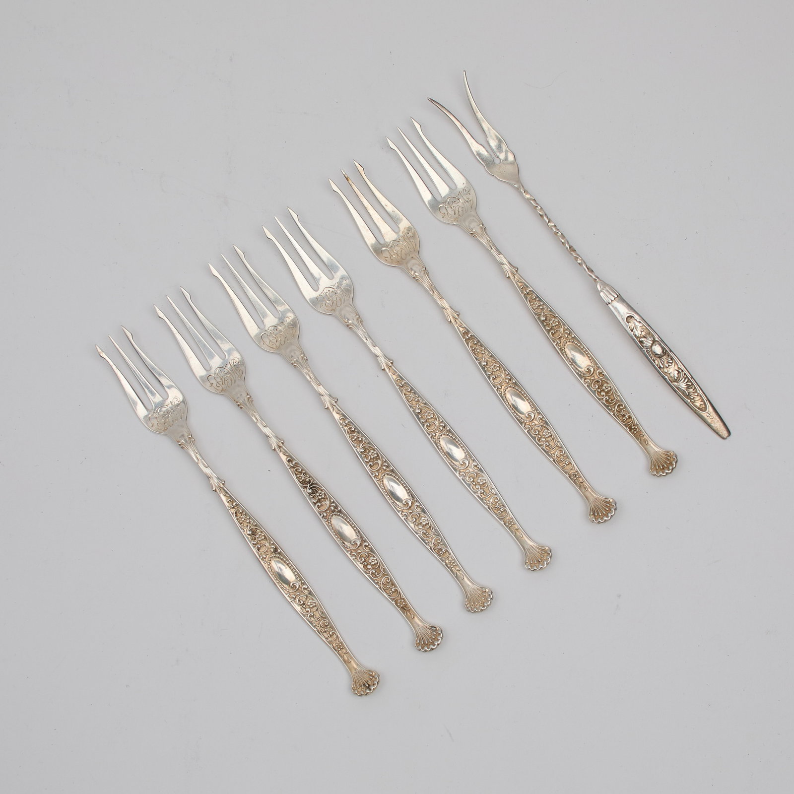 Sterling Estate Cocktail Forks: A set of six (6) sterling cocktail forks by J.E. Caldwell co., alongside one (1) sterling pickle fork. Each marked sterling. Total approximate weight : 103.99 grams. Provenance: property of a Jamestow