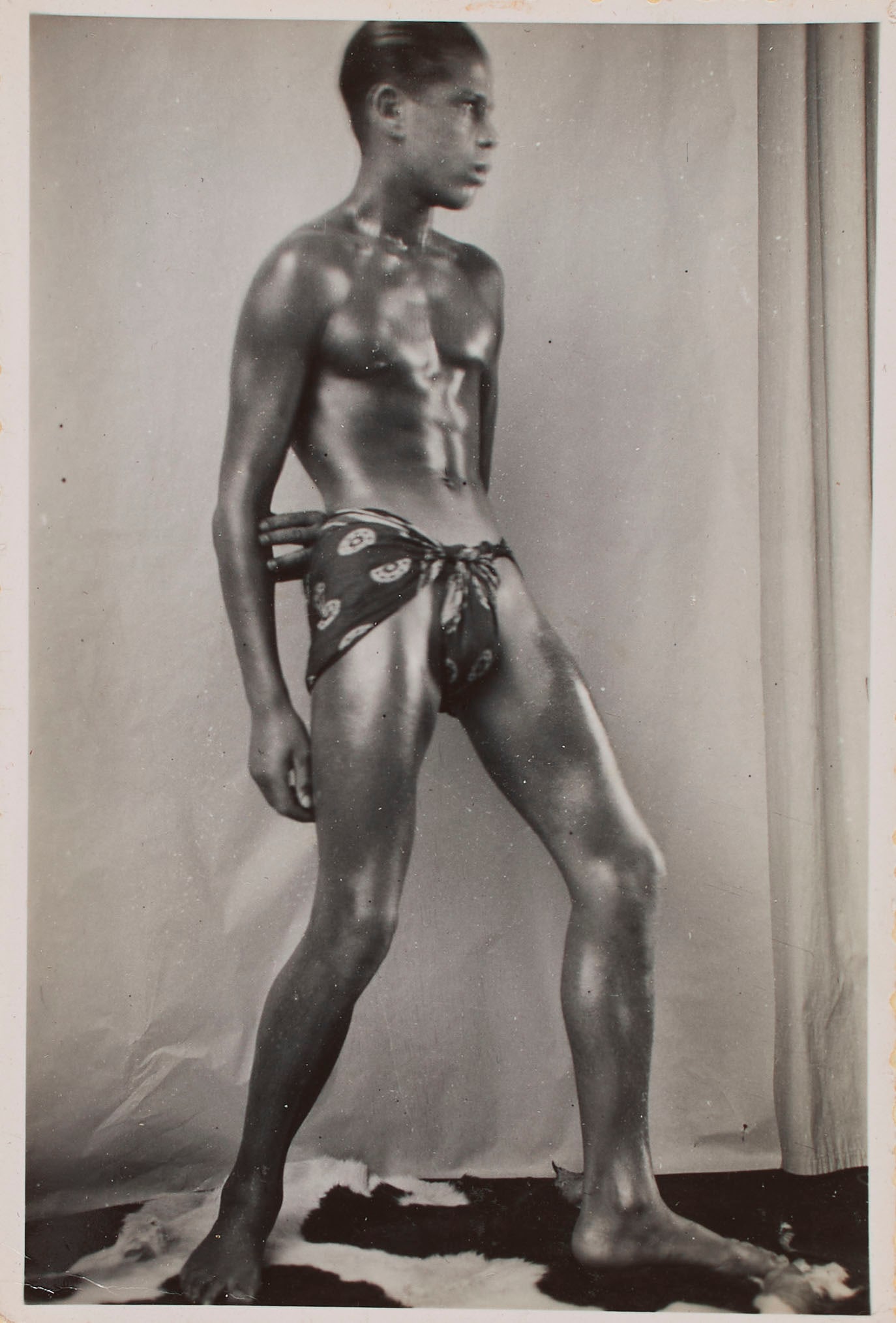 Queer Libertine Europe (1920s): A scarce to find photograph, circa 1920s, depicting a partially naked African male modeling provocatively. We speculate the model is a performer for one of the Josephine Baker era Paris folies. Printe