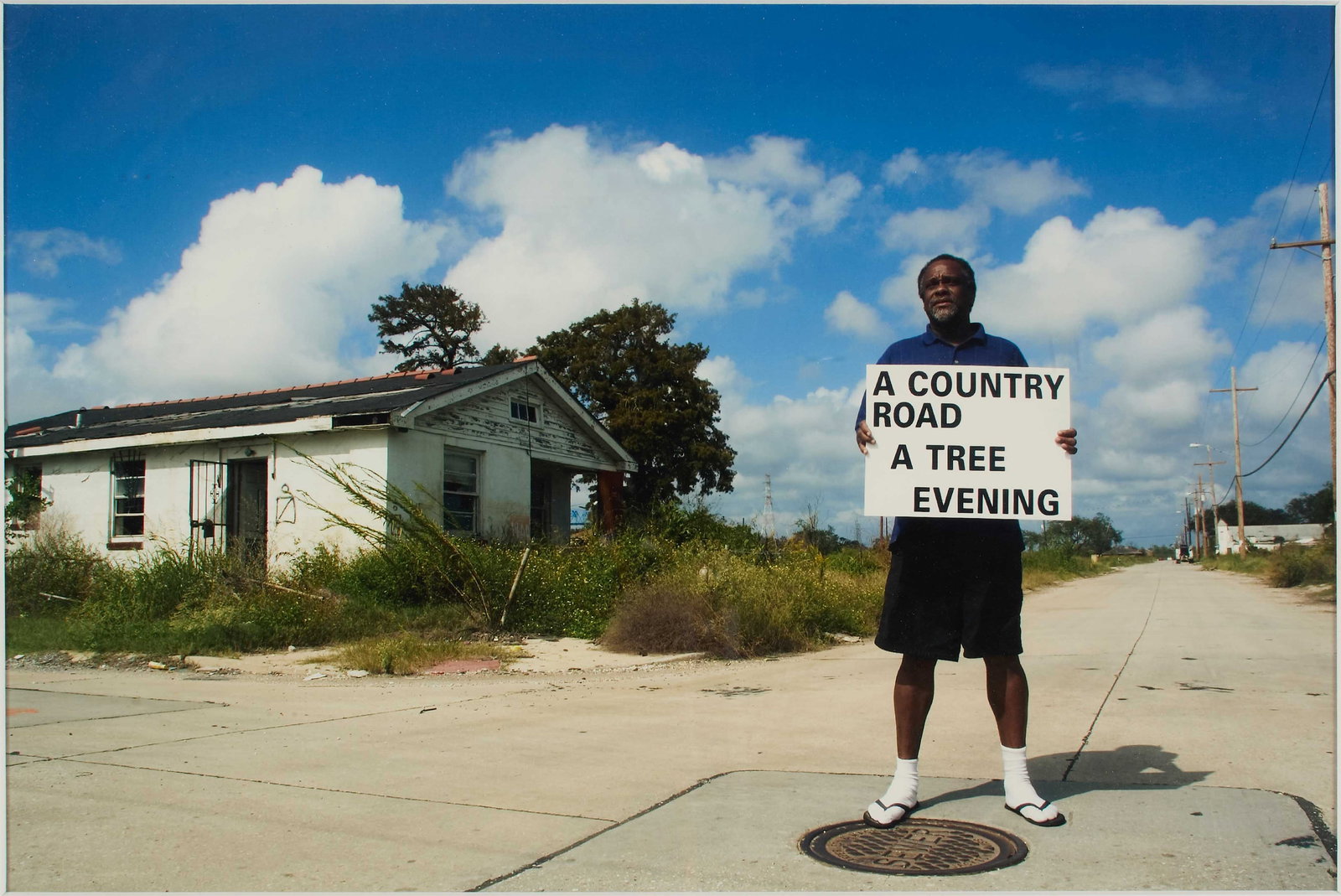 Paul Chan (American, b. 1973): Untitled (Robert Lynn Green Sr., a resident of New Orleans' Lower Ninth Ward, with a sign by the artist, with the first three lines of Samuel Beckett's "Waiting for Godot" in block t
