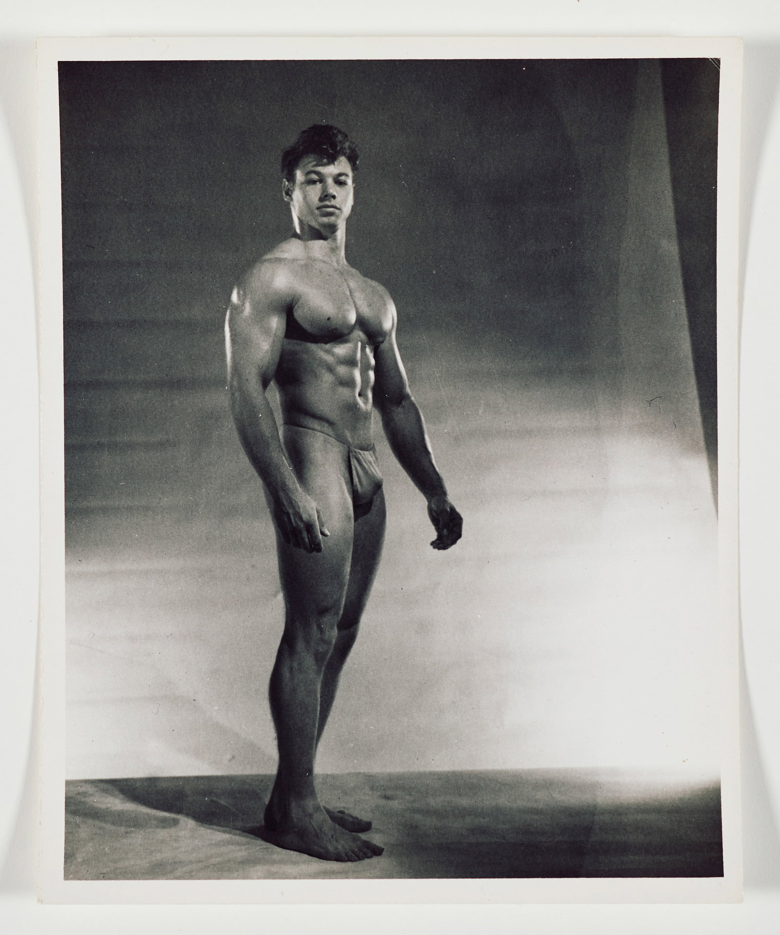 Robert Mizer (Athletic Model Guild) (1922-1992): Kim Fox. Gelatin silver print. Annotated in pencil on the verso, "YE 5 B 14". 8 x 10 in (20.3 x 25.4 cm). Provenance: Property of a Private California Collection.