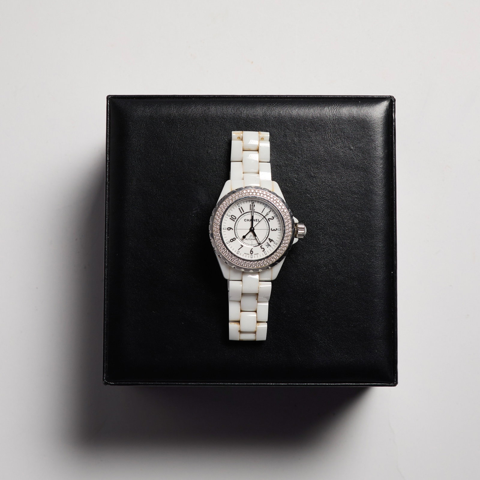 Chanel (French, Est. 1910): A Chanel J12 Watch. Diamond studs around the bezel. Opalescent white ceramic band. Two extra links included. In original box. Automatic. Functioning. 
