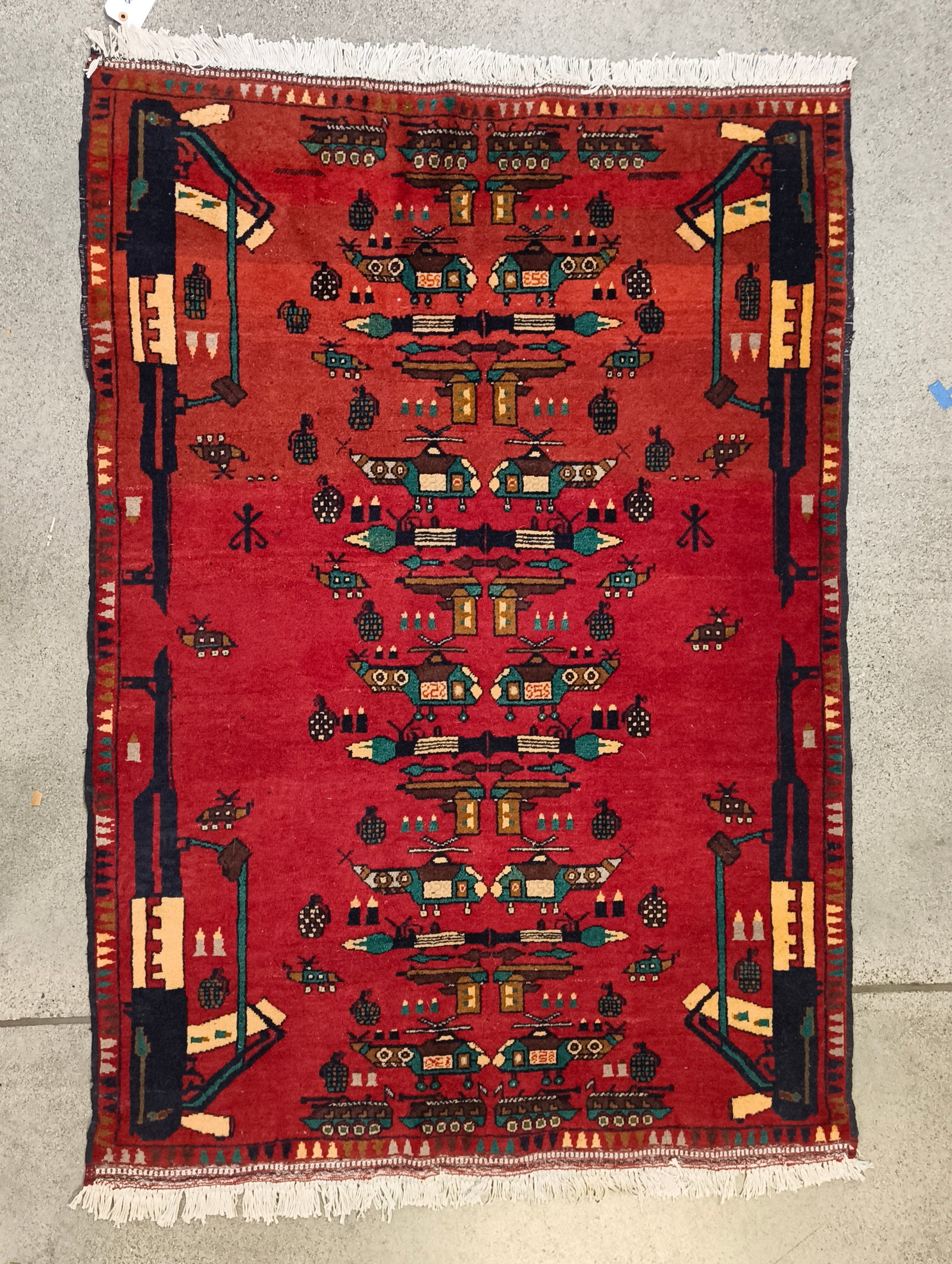 Hand Knotted Afghan War Rug: A hand knotted Afghan war rug depicting an arsenal of stylized automatic rifles, grenades, rocket launchers, tanks, helicoptors, armored personel carriers, pistols and ammunition. 20th Century. 7