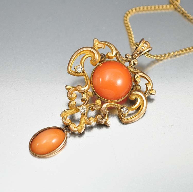 From the first decade of the twentieth century, a roman: from the first decade of the twentieth century, a romantic art nouveau necklace pendant fashioned in the iconic, curvaceous whiplash design, centered with a rich coral glass stone and a similar drop p