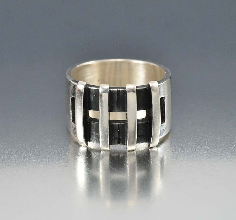 Exquisite sterling silver ring in a mid century moderni: exquisite sterling silver ring in a mid century modernist design. the wide band ring features a split front having black enamel and four vertical bars over the center. the band graduates ever so sligh