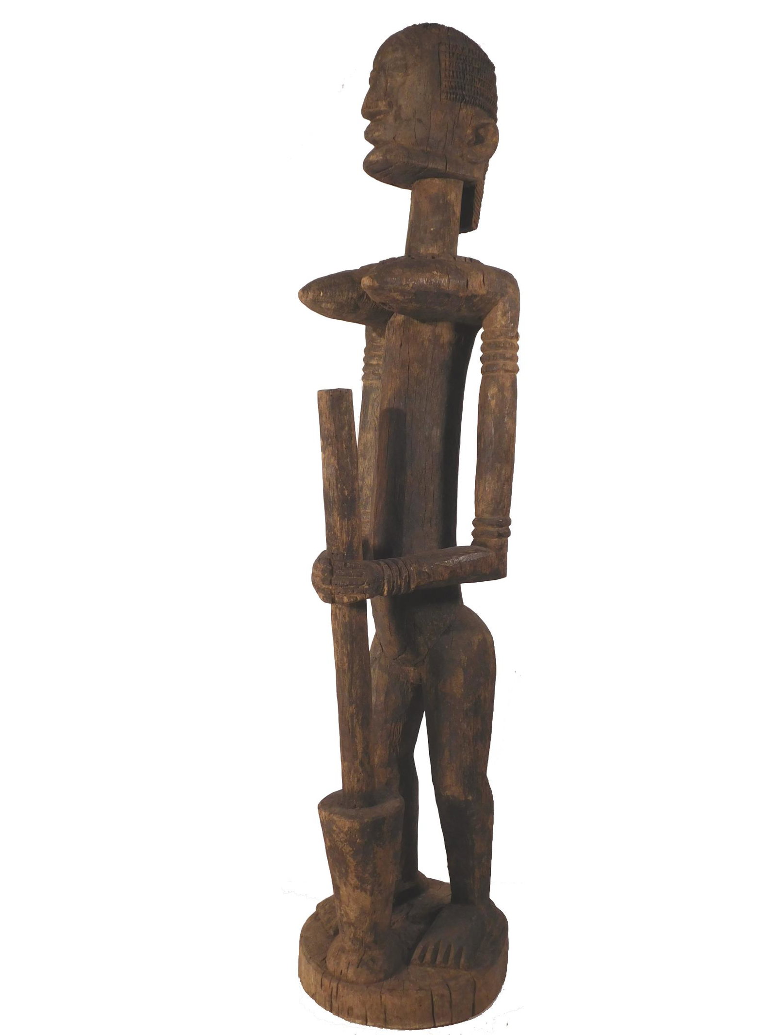 Dogon Woman Antique African Sculpture: Dogon Woman with a Mortar and Pestle., Wood, 47 inches high. This traditional depiction of a woman shows a female hair style and also a beard. Its estimated age is late 19th Century (Circa 1880). Over