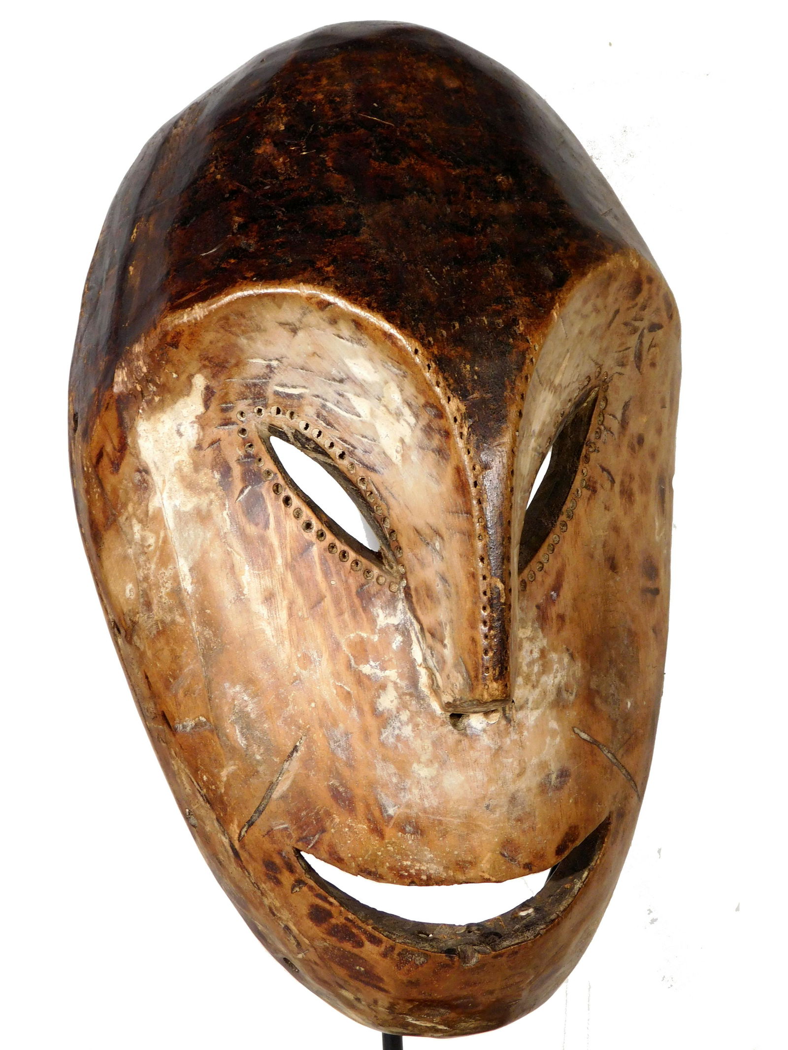 Mask, Mbole People, Congo/Zaire, with Stand: Mbole People, Congo/Zaire: Mask, carved wood in the shape of an abstracted smiling face, with incised dots defining the eyes and nose, and longer incisions above each corner of the mouth. The hair is